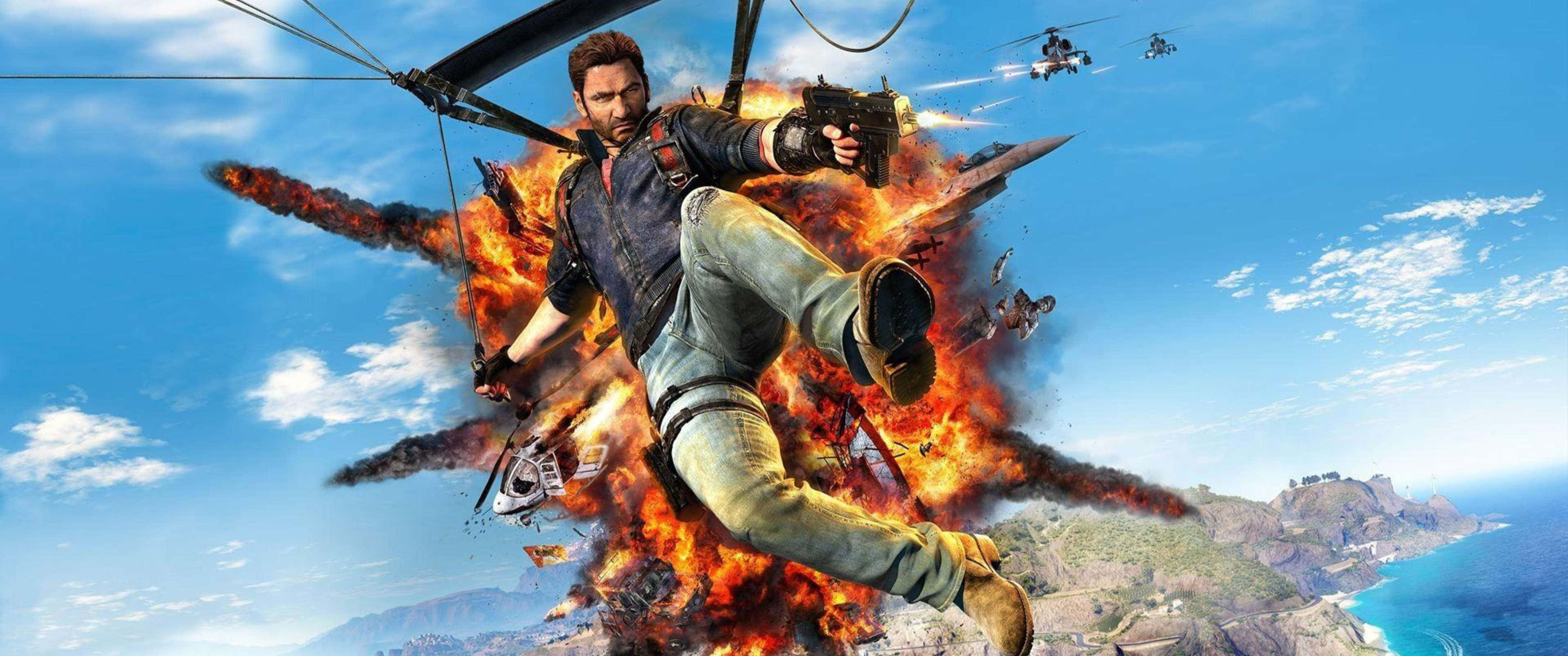 3440x1440p《Just Cause 4》Rico Rodriguez 背景 壁紙 — 一名男子從燃燒的直升機上懸掛在半空中，下方是海岸景觀，身後發生爆炸。