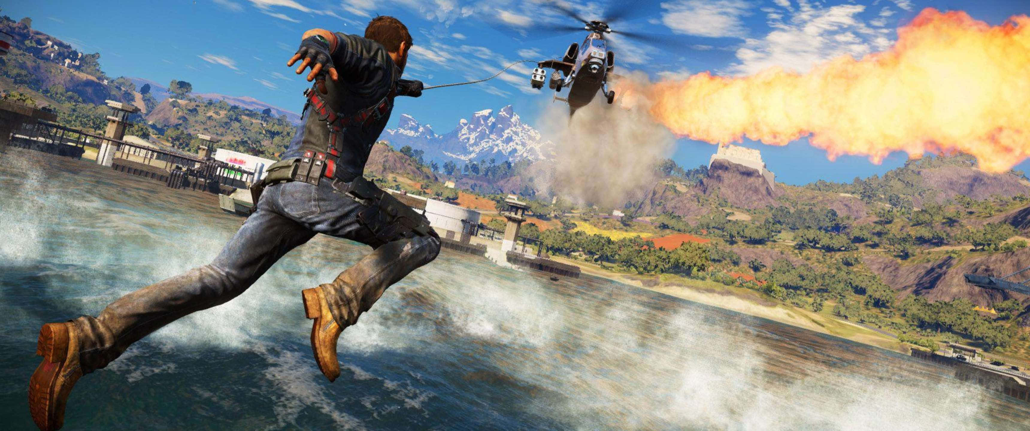 3440x1440p《Just Cause 4》戰鬥場景背景 壁紙 — 一名男子跳過水面，身後有直升機發射火焰，背景為山巒。