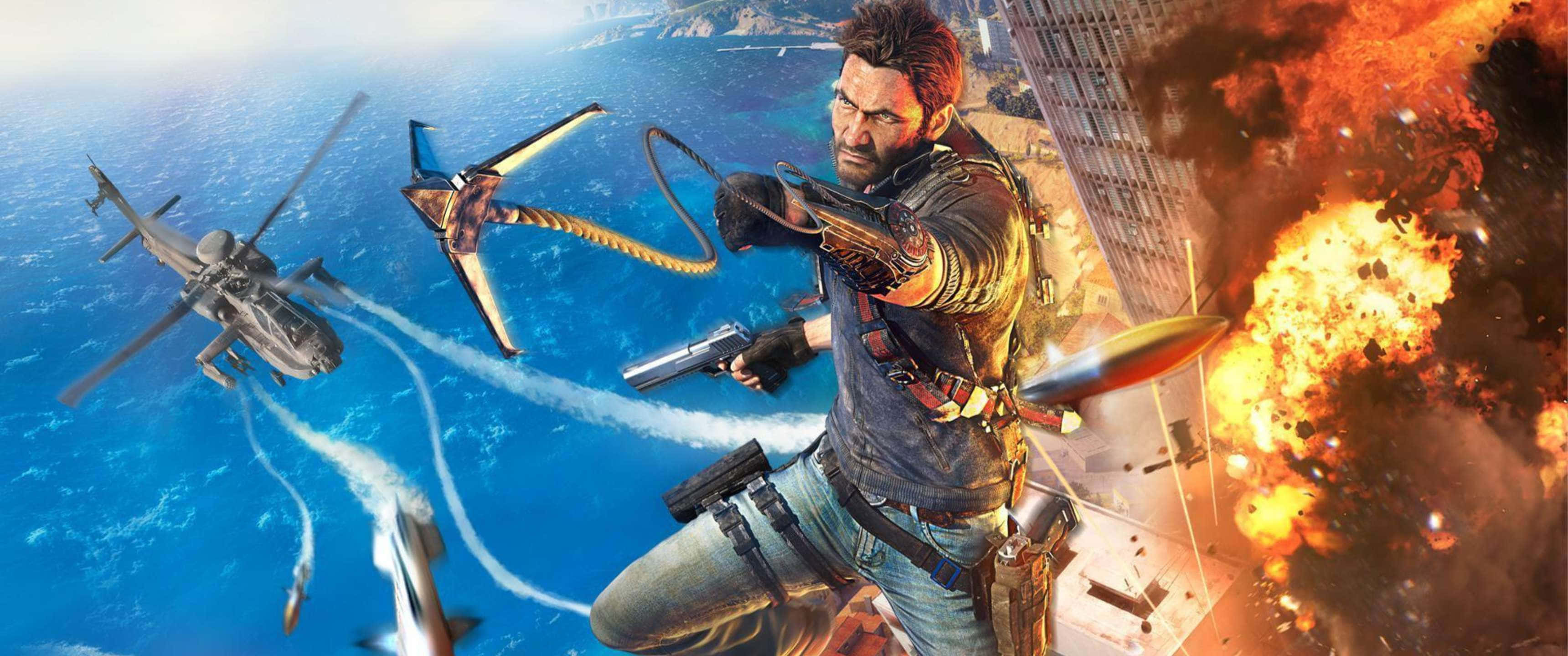 3440x1440p《Just Cause 4》遊戲玩法背景 壁紙 — 一個粗獷的男人掛在抓鉤上開火，下方是燃燒的城市，天空中有直升機和戰鬥機。