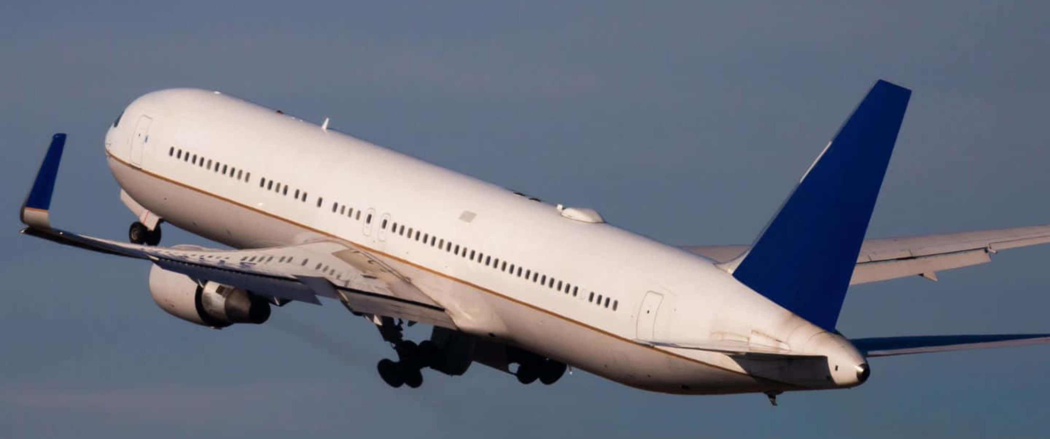 雄偉巨型客機翱翔天際 3440x1440p 圖像 壁紙 — 一架白色商用飛機帶有藍色尾翼，在晴朗藍天中飛行，起落架已放下。