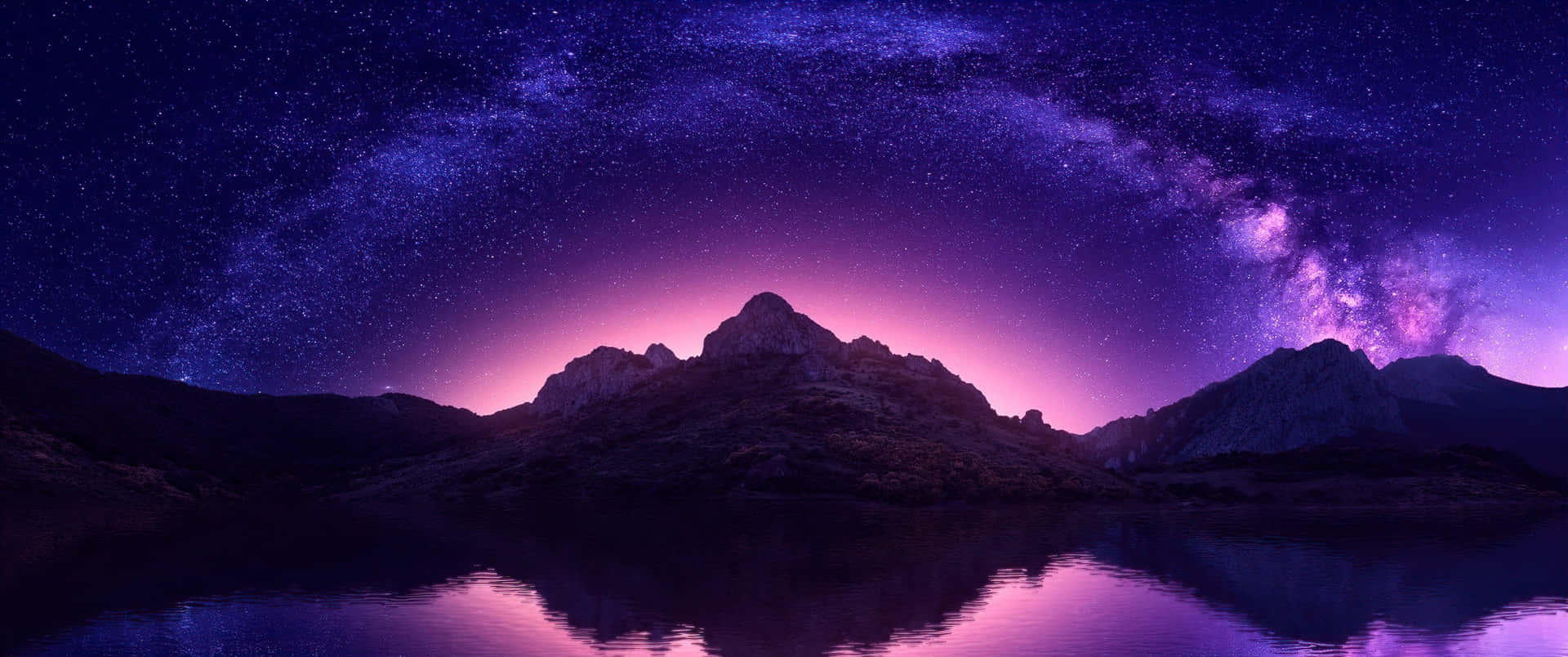 紫色和藍色的山脈在平靜的水面上倒映，星空中有銀河。