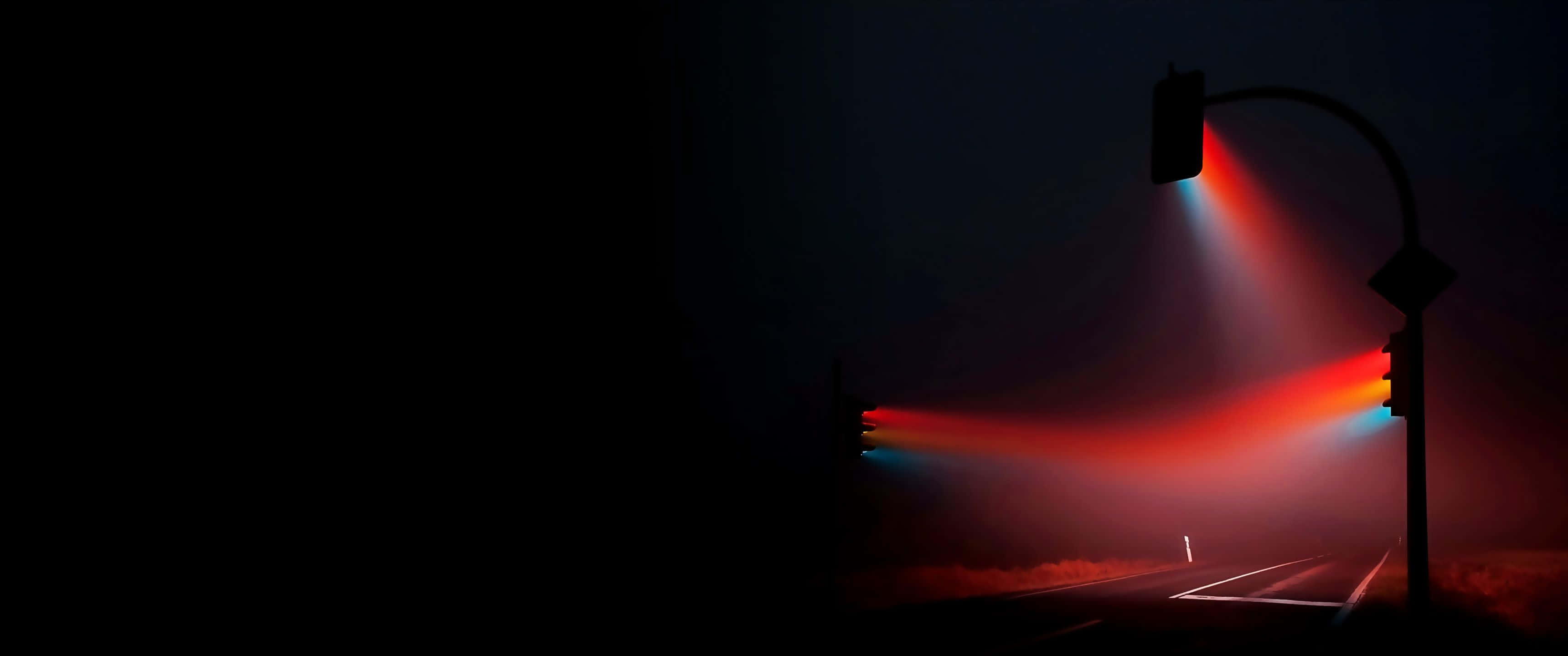 3440x1440p 暗夜道路與交通燈背景 壁紙 — 夜晚一條孤獨的道路，被發光的紅色和藍色交通燈照亮，透過迷霧投射出戲劇性的光束。