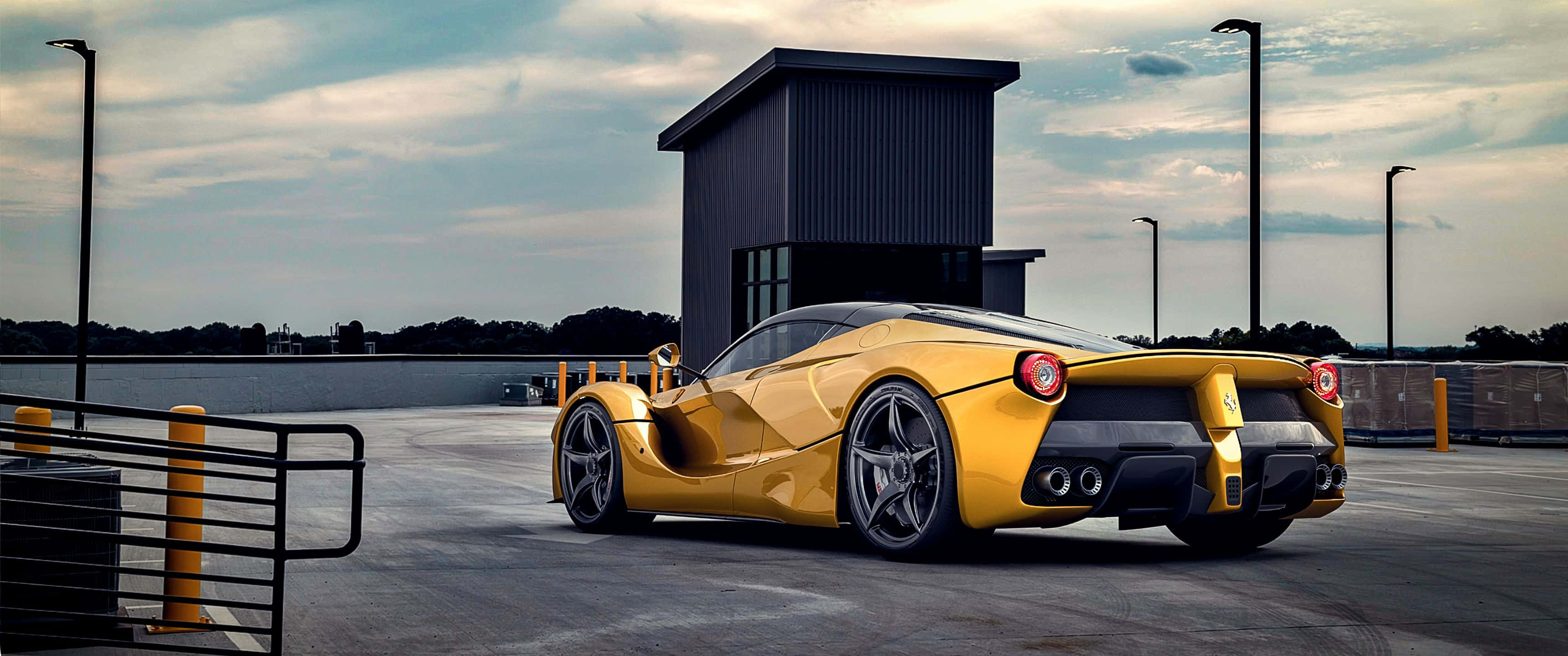 3440x1440p 法拉利 LaFerrari 背景 壁紙 — 一架鮮黃色法拉利LaFerrari停泊在混凝土停車場，旁邊係一棟現代灰色建築物，天空多雲。