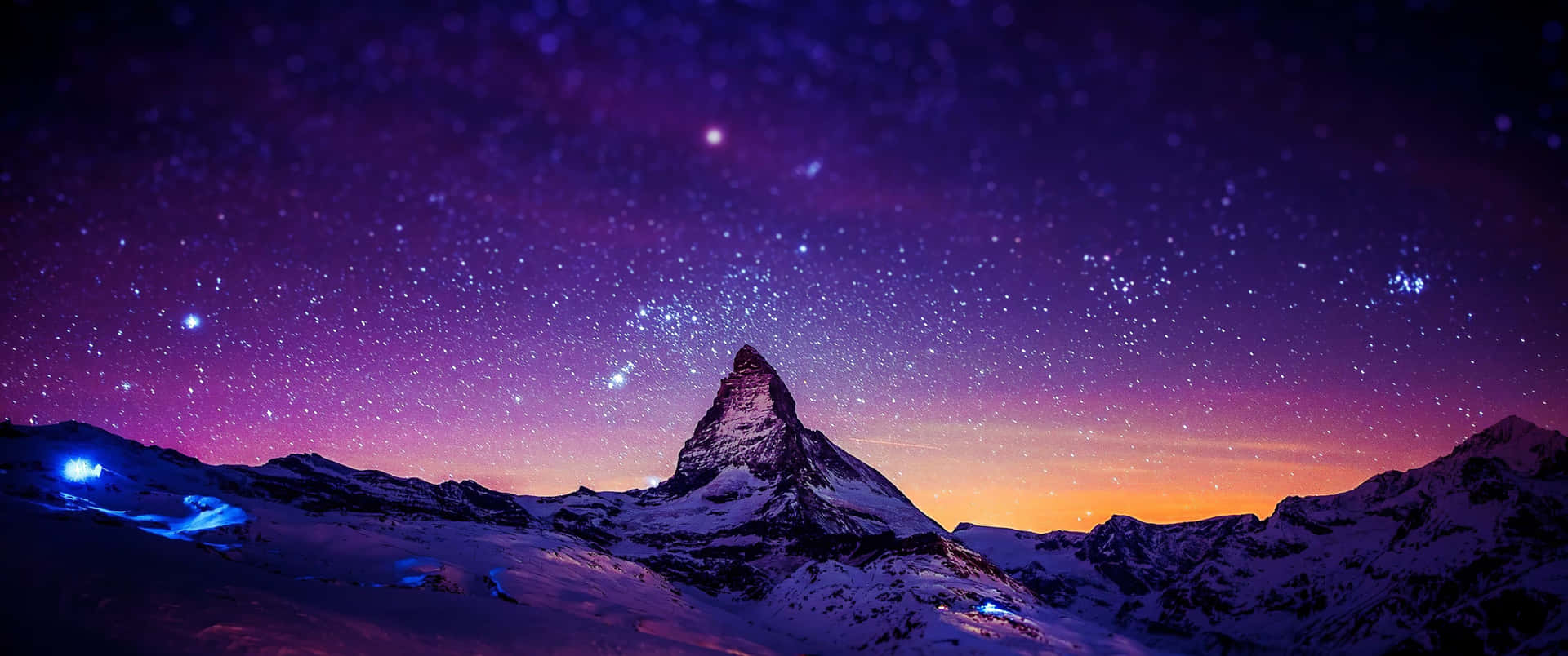 在星空紫色和橙色夜空下的雪山頂。