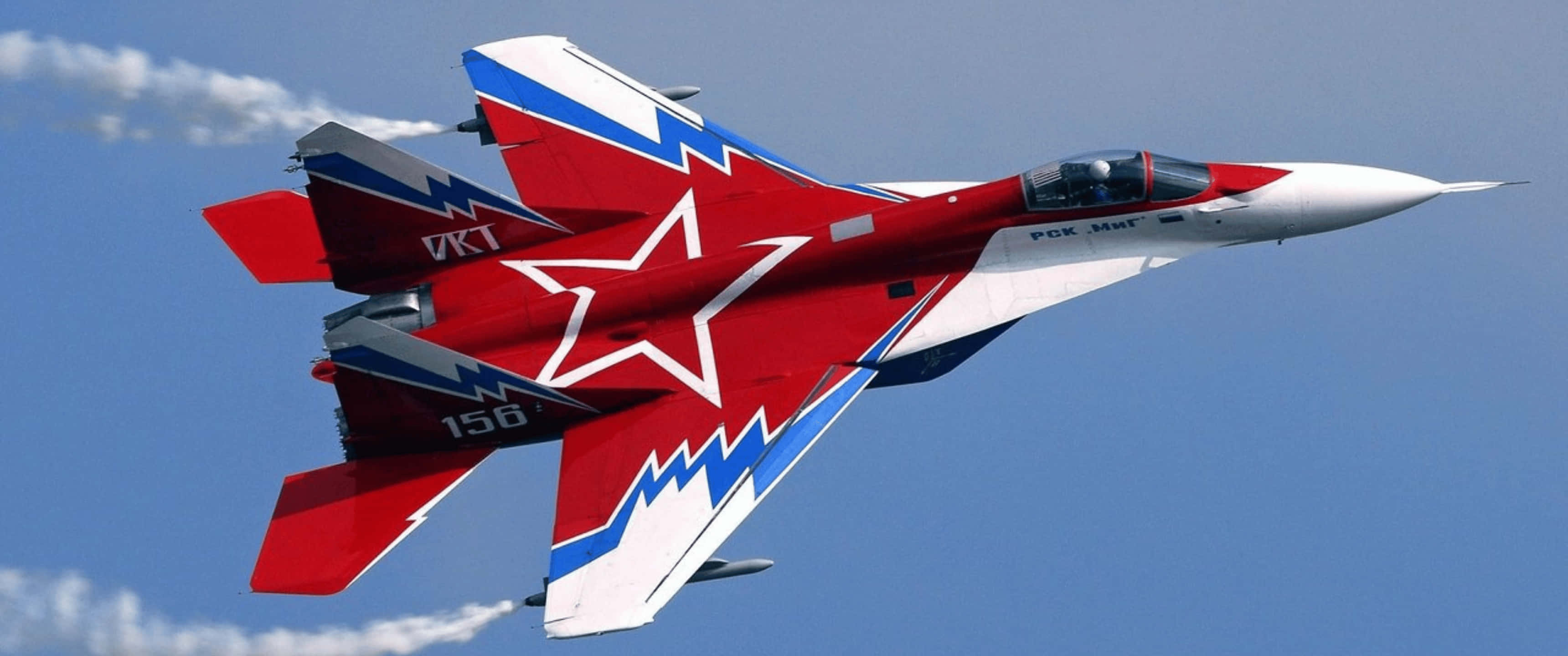 3440x1440p 飛機 Mig-29 OVT 背景 壁紙 — 一架紅白藍色戰鬥機帶有大型星星貼紙，在清澈的藍天中翱翔，留下白色凝結尾跡。