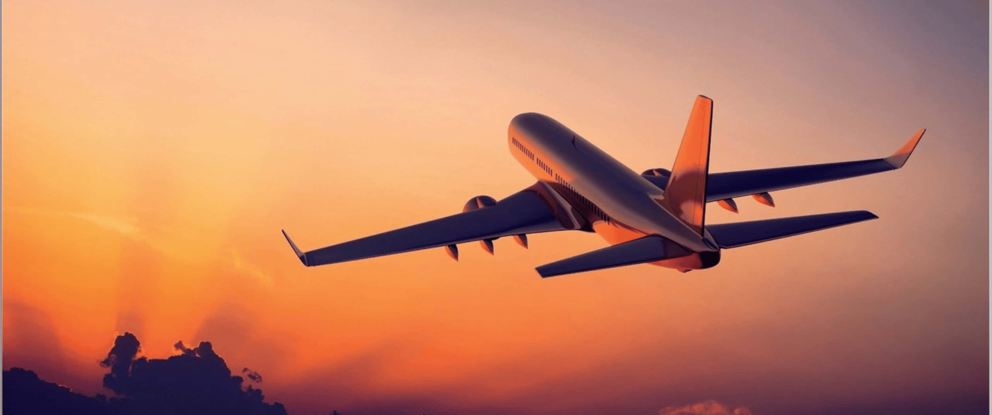 3440x1440p 飛機飛越夕陽天空背景 壁紙 — 一架大型客機在下方烏雲密佈的背景下，翱翔於火紅橙色的日落天空。