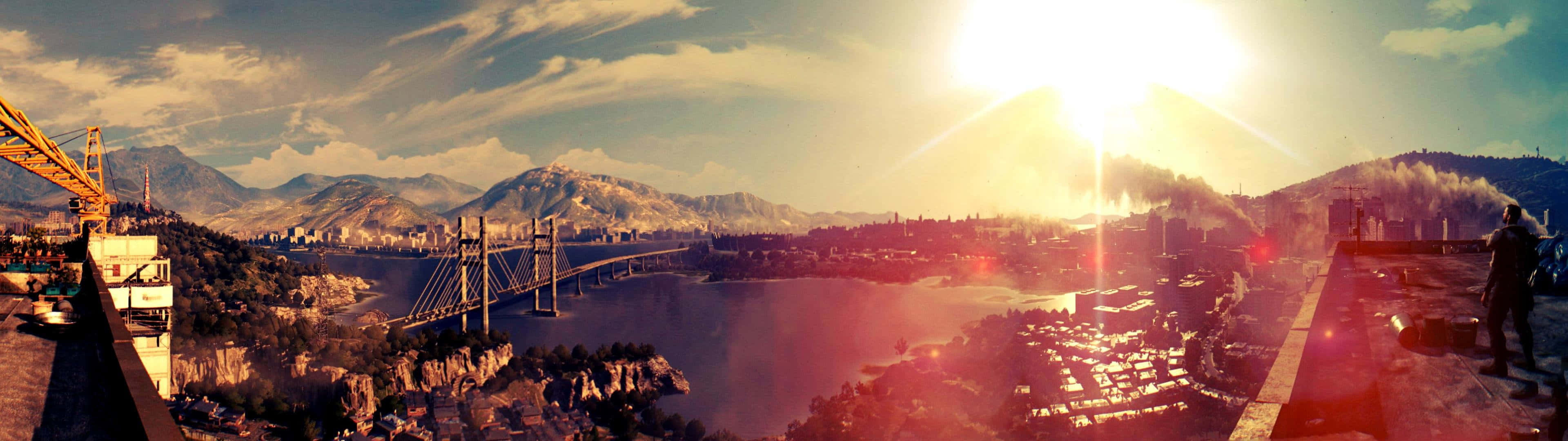 3840 X 1080 遊戲壁紙：消逝的光線全景 壁紙 — 廣闊城市全景日落景觀，河流上橫跨一座橋樑，背景是山脈。