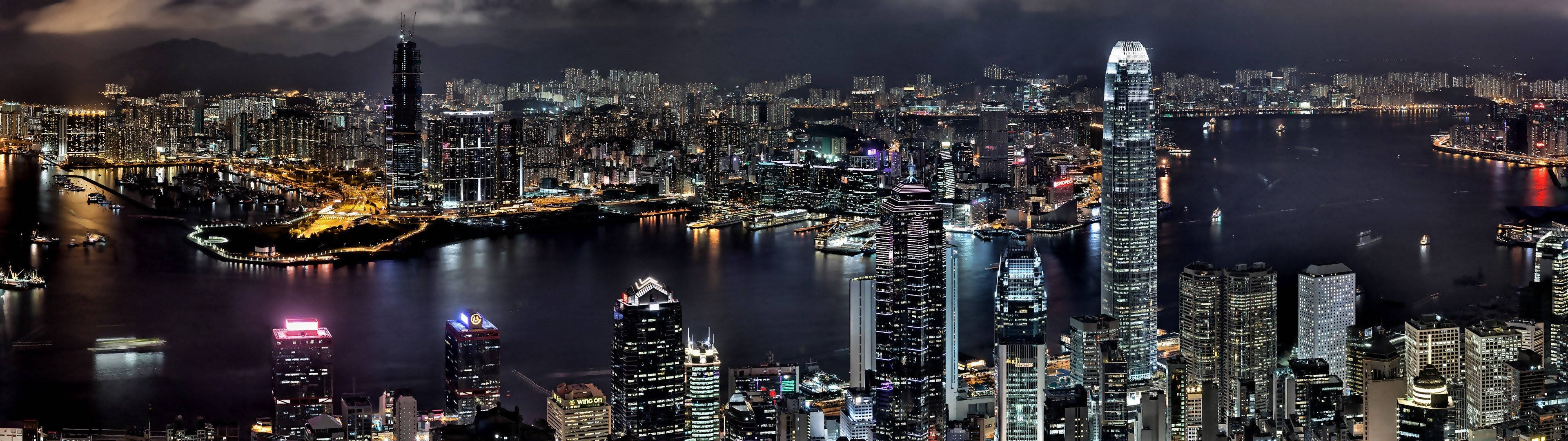 夜晚的香港天際線，燈火通明的摩天大樓和港口船隻。