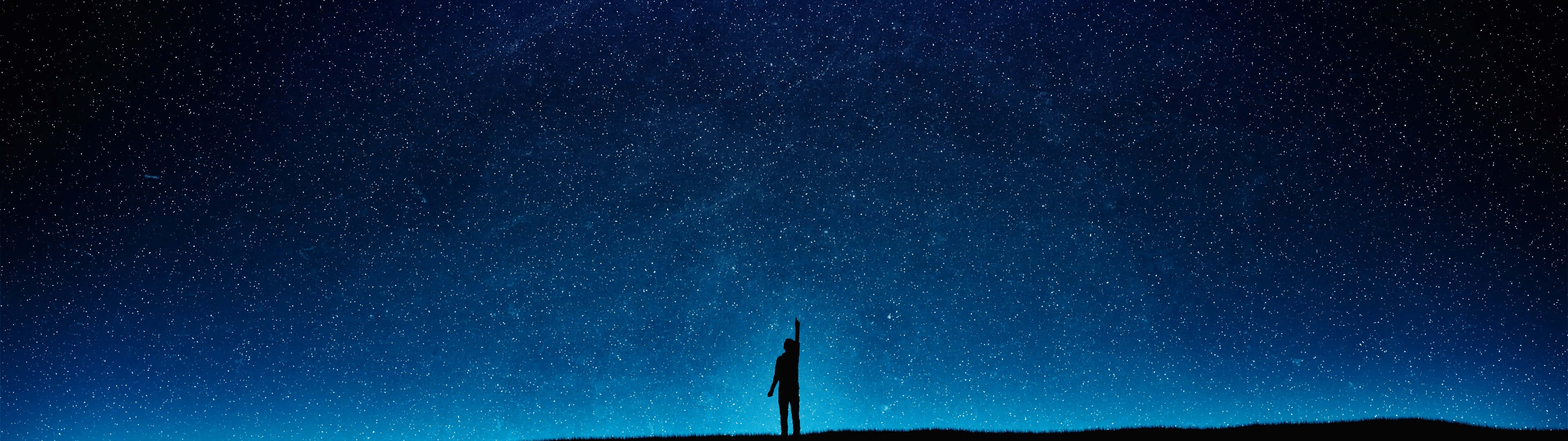 一個人獨自站在山丘上，在星空下。
