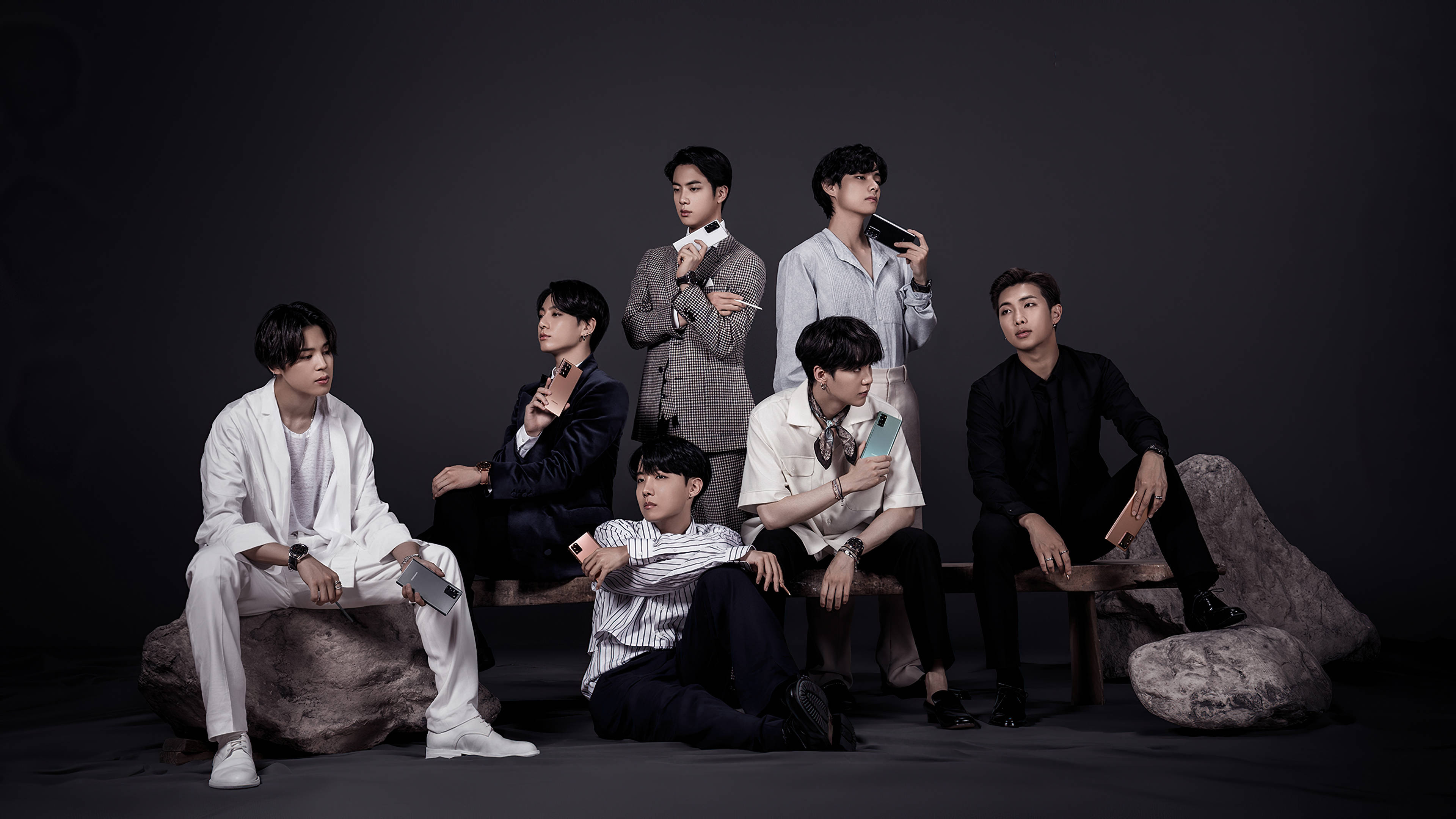3840x2160監視器壁紙 BTS男孩 壁紙 — 七位時尚男士在深色工作室背景下，於質樸的木長椅上拿著智能手機擺姿勢。