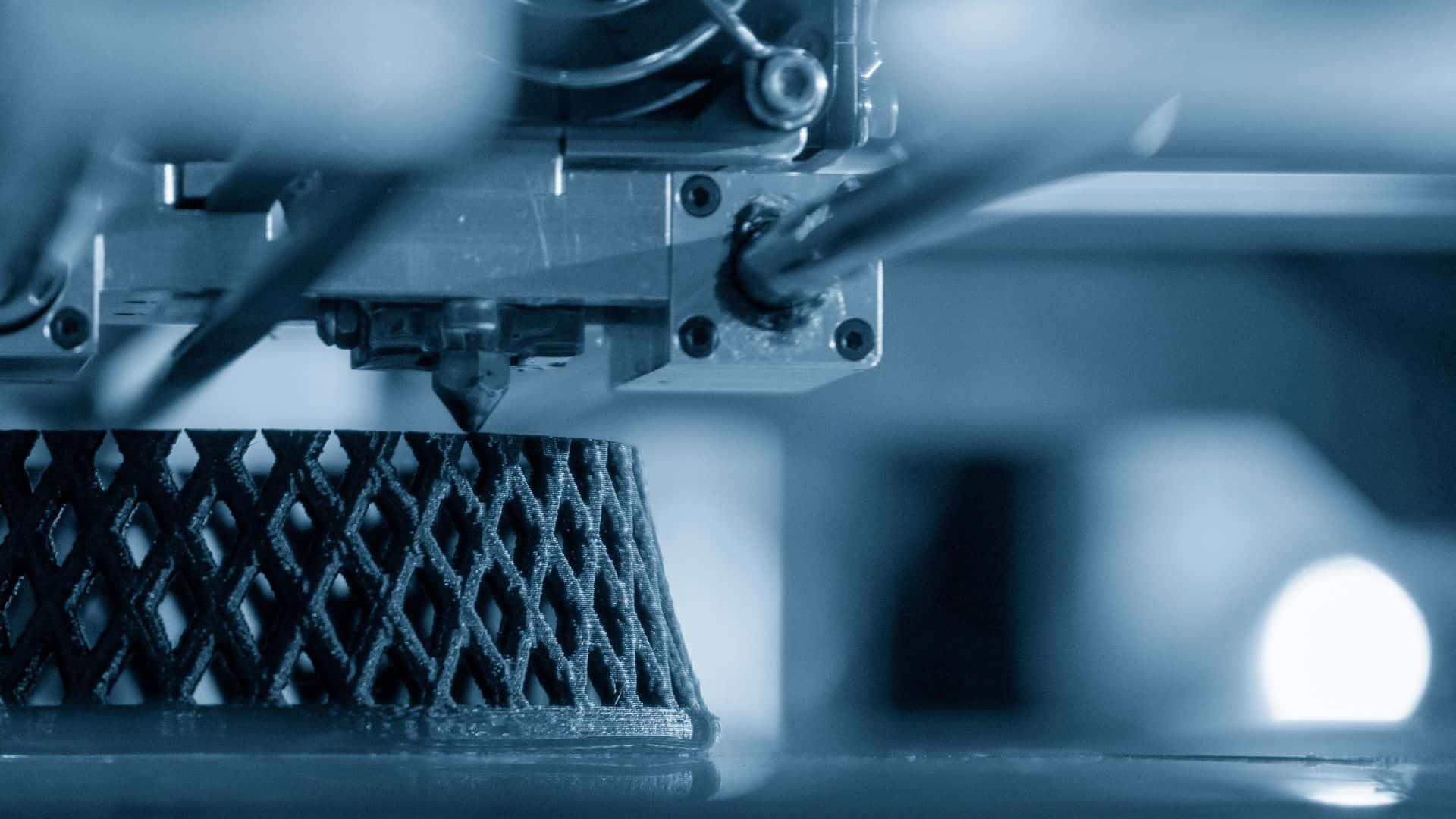 3d Printer 桌布 壁紙 — 3D打印機在冷藍色燈光下擠出分層塑料以形成幾何網格結構的特寫。