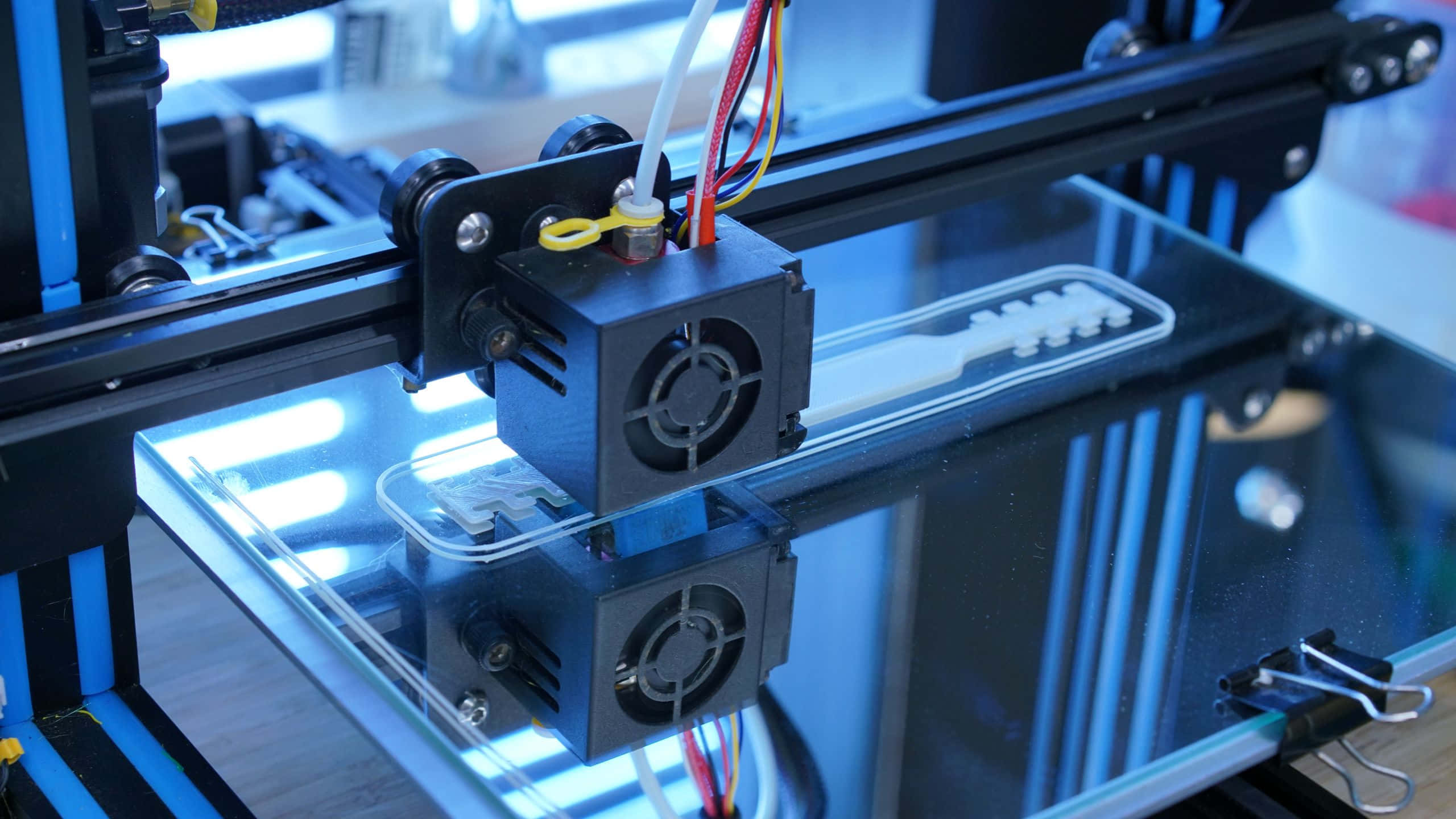 3d Printer 桌布 壁紙 — 3D打印機擠出器在藍光下將白色線材沉積到玻璃打印平台的特寫。