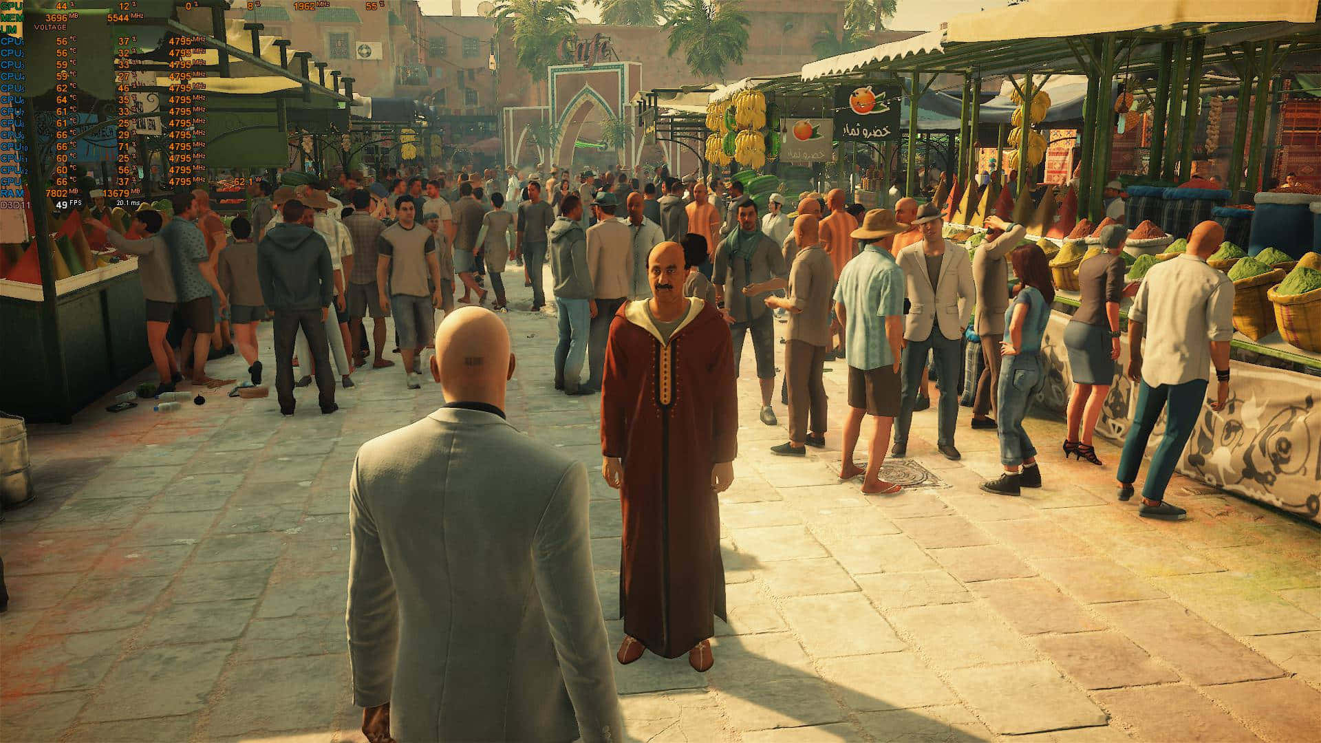 特工47置身於《Hitman 2》的行動中心 壁紙 — 一個光頭男子穿著灰色西裝，在溫暖的金色陽光下，穿過一個充滿商販和購物者的繁忙中東市場。