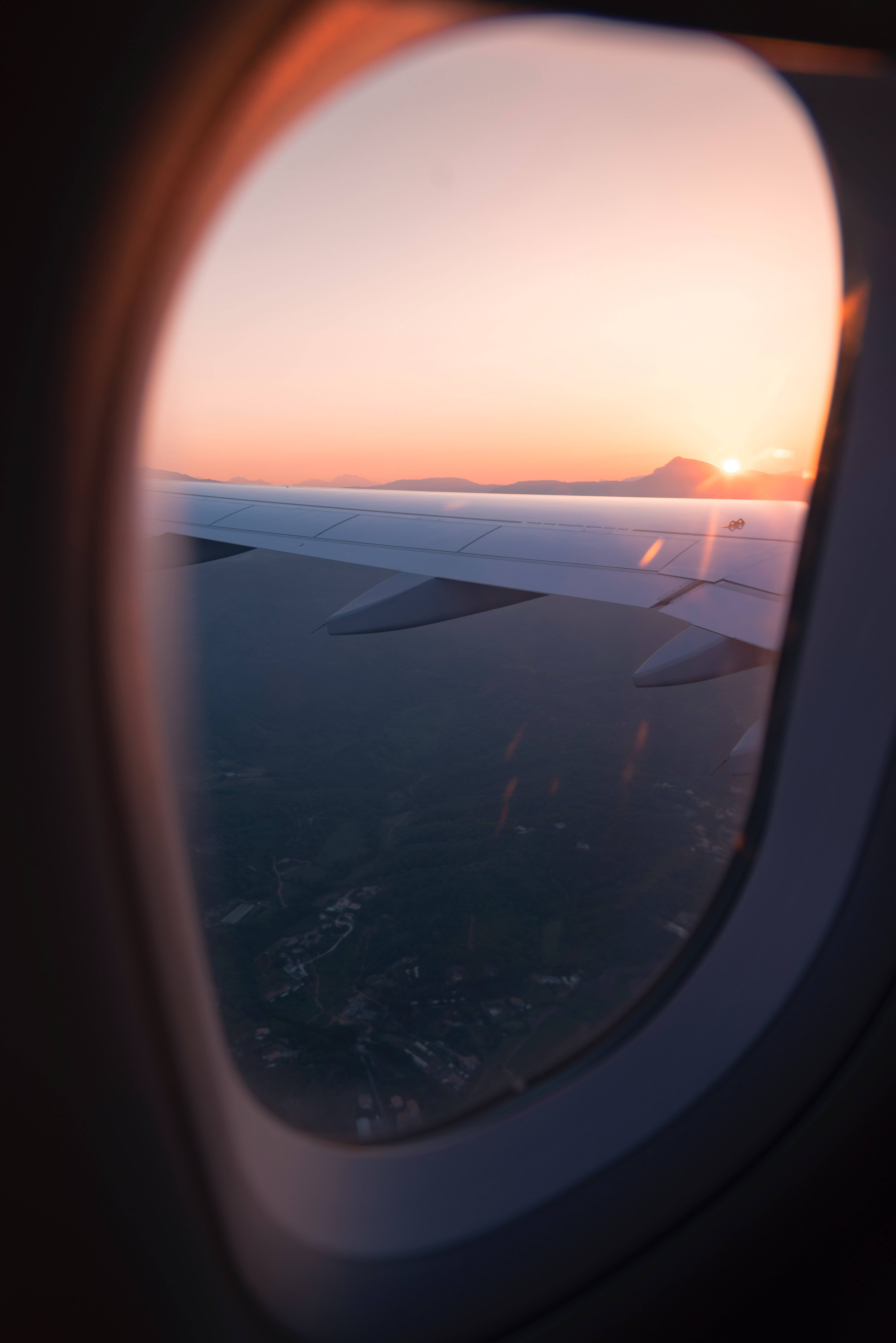 飛機窗外夕陽 4K 壁紙 — 飛機機翼剪影，襯托著從飛機窗戶看到的鮮豔橙色日落。
