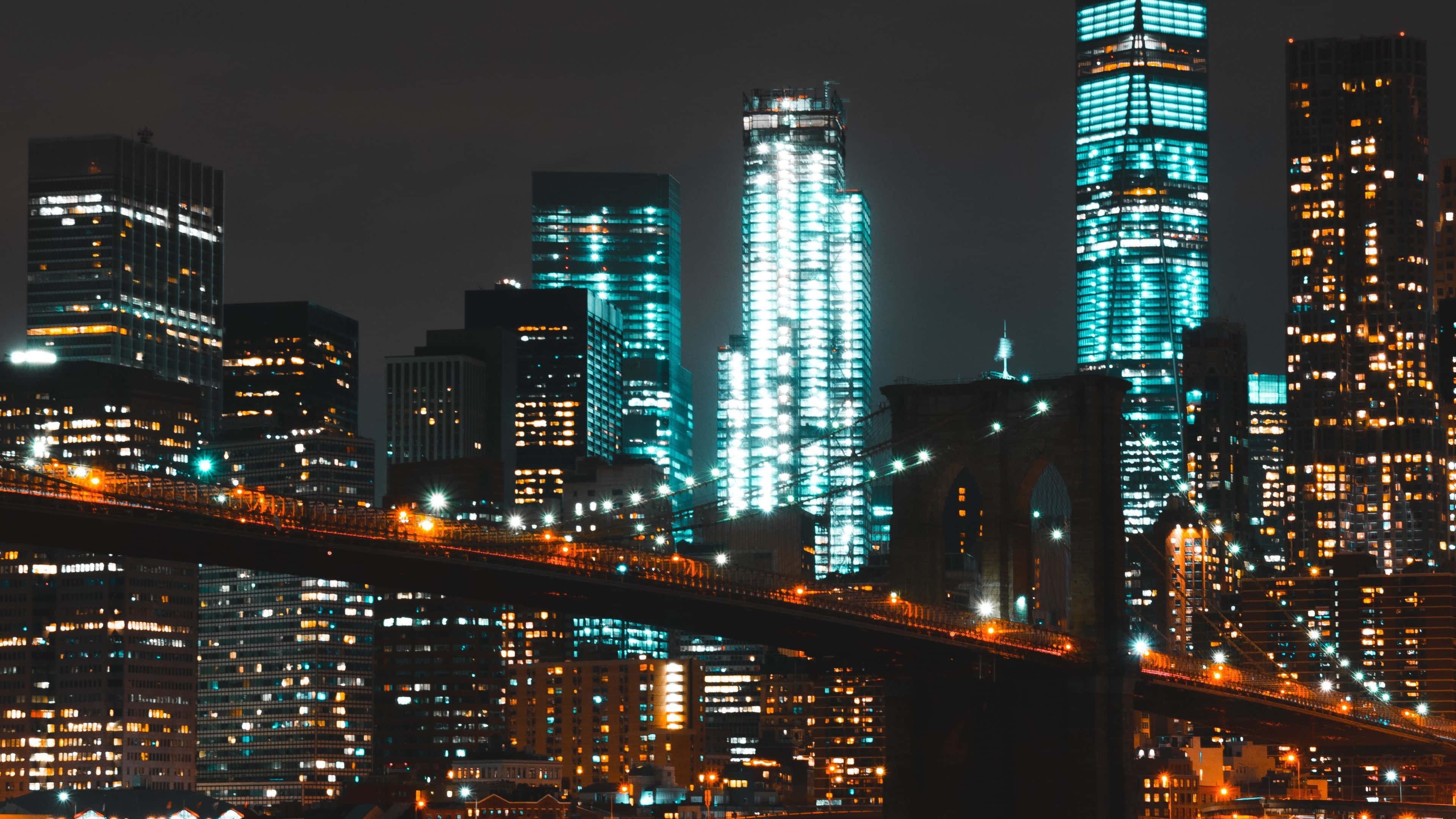 4K 紐約市夜間布魯克林大橋 壁紙 — 充滿活力的夜景城市景觀，以黑暗天空為背景，閃爍的摩天大樓和亮燈的橋樑。