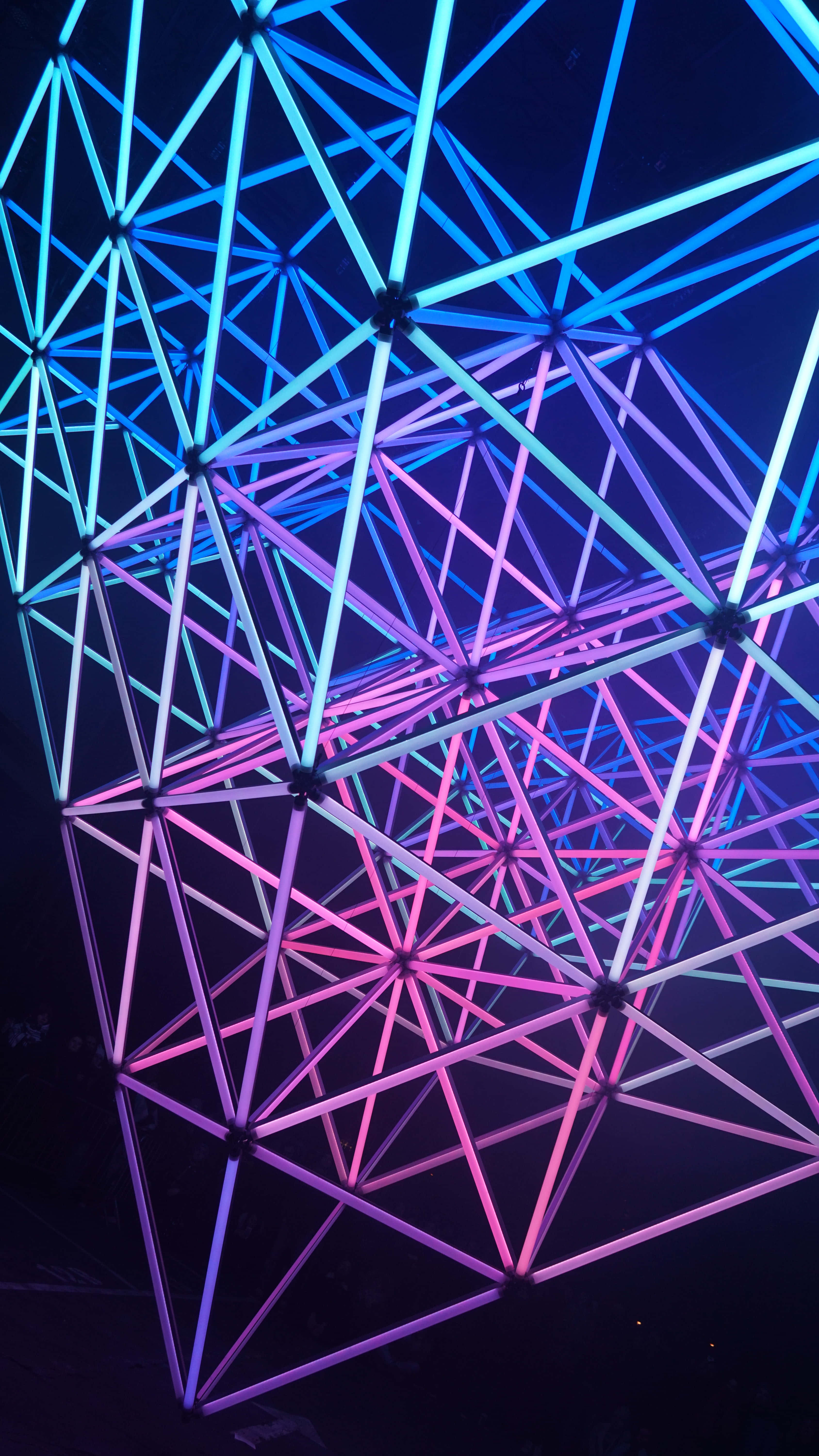4K AMOLED 背景 粉藍霓虹燈光 壁紙 — 由霓虹藍和粉紅管組成的發光幾何格柵，在黑暗背景上形成一條未來感隧道。