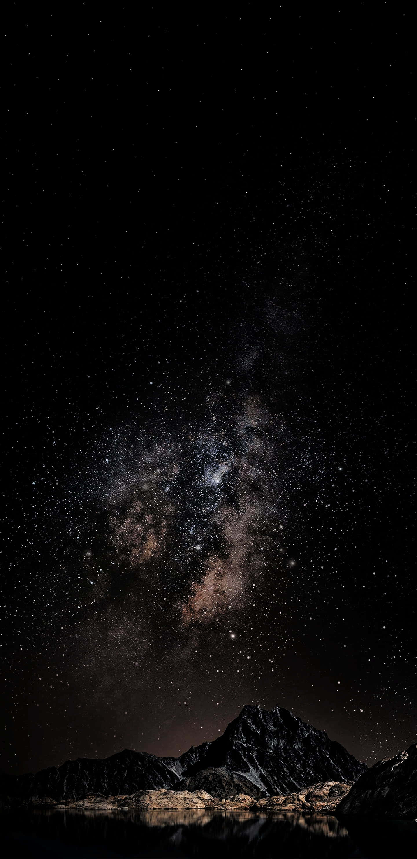 4K AMOLED 背景：群山與繁星 壁紙 — 令人嘆為觀止的夜空，佈滿無數星辰，銀河在平靜水面倒映的黑暗山脈上空拱起。