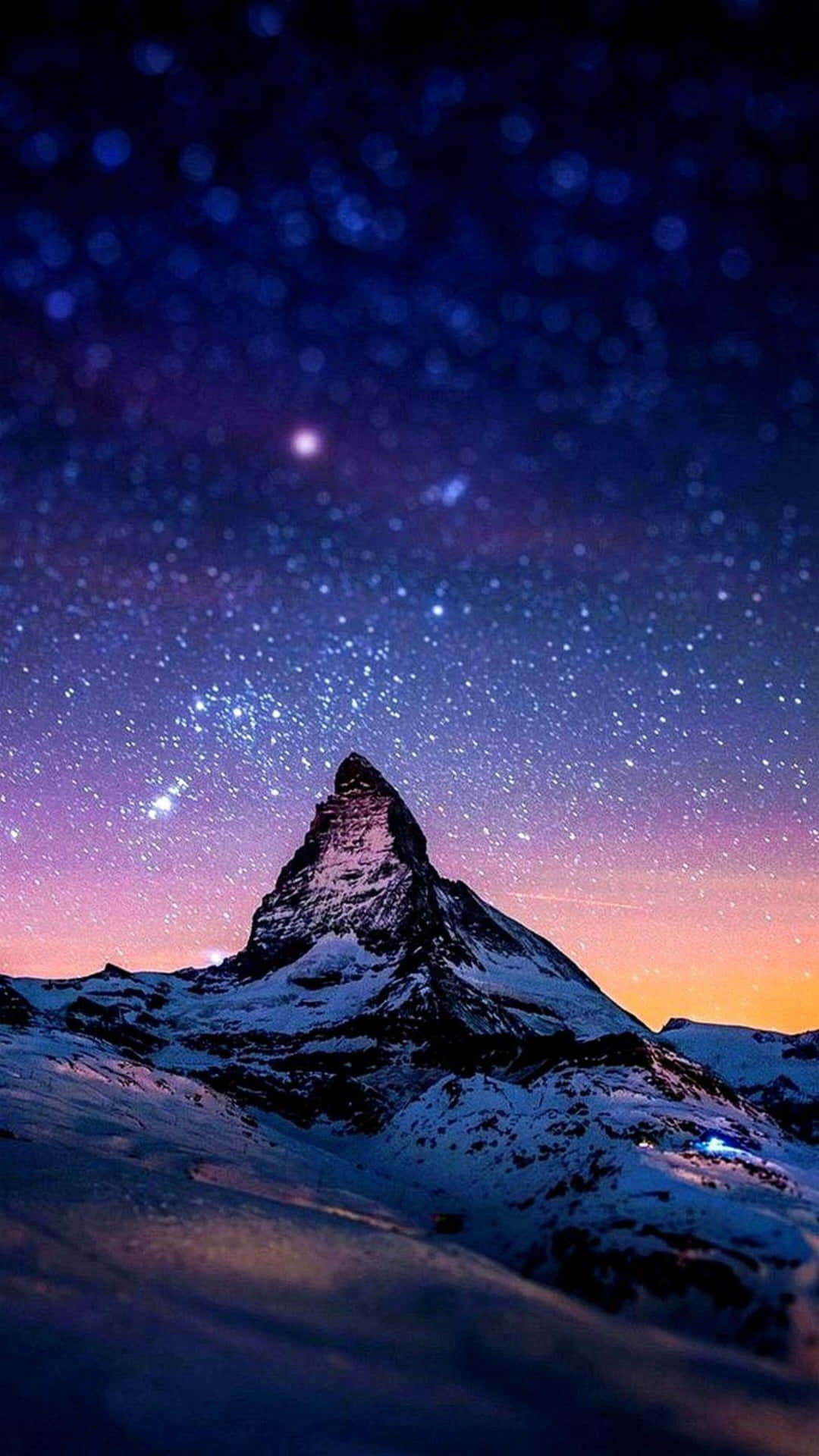 星空暮色下帶有紫色和橙色色調的雪山峰。