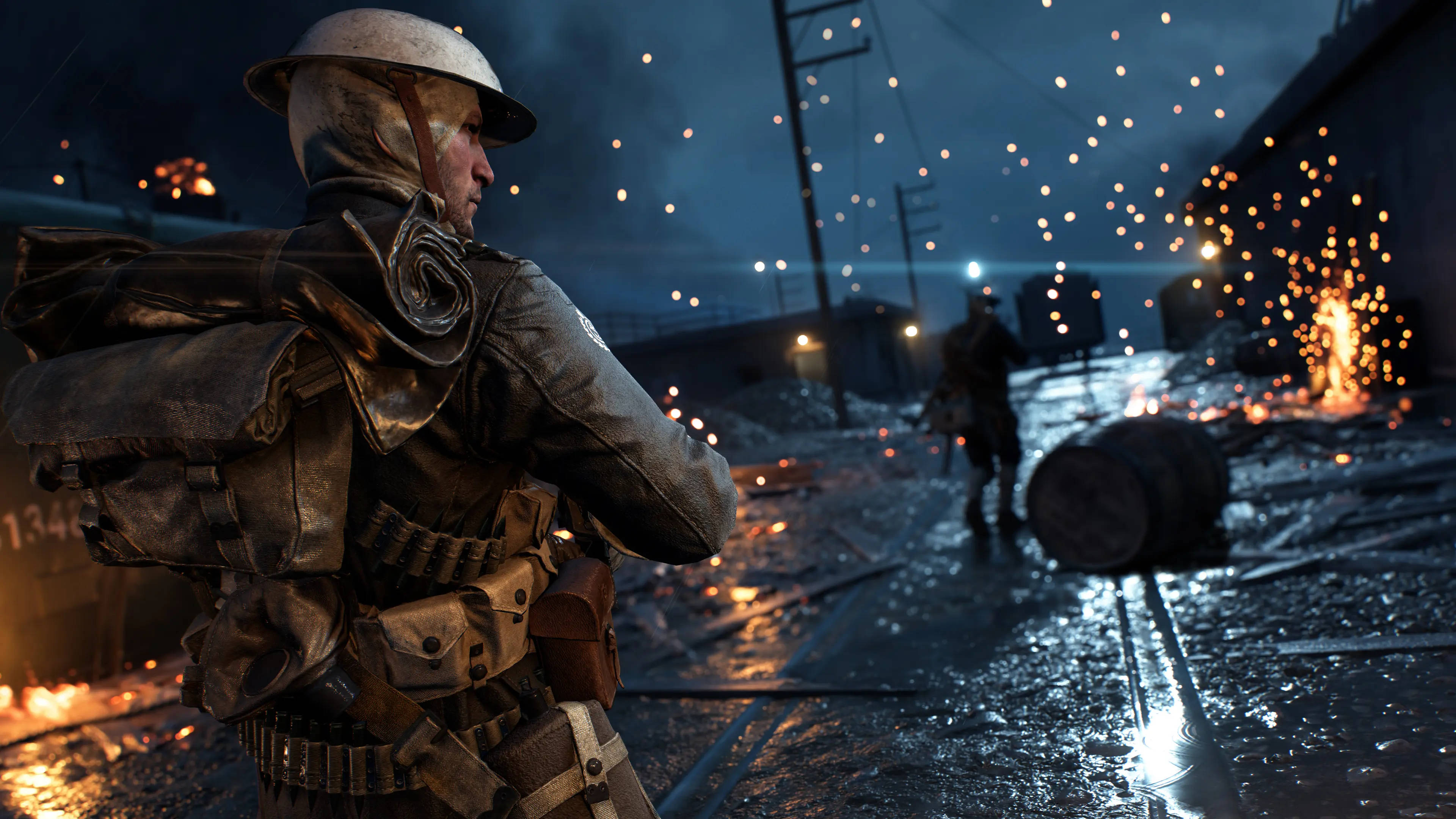4K BF1 英軍士兵俯瞰廢墟 壁紙 — 一名戴著頭盔和裝備的士兵在夜晚的雨淋戰場上站立，遠方爆炸產生的火花飛舞。