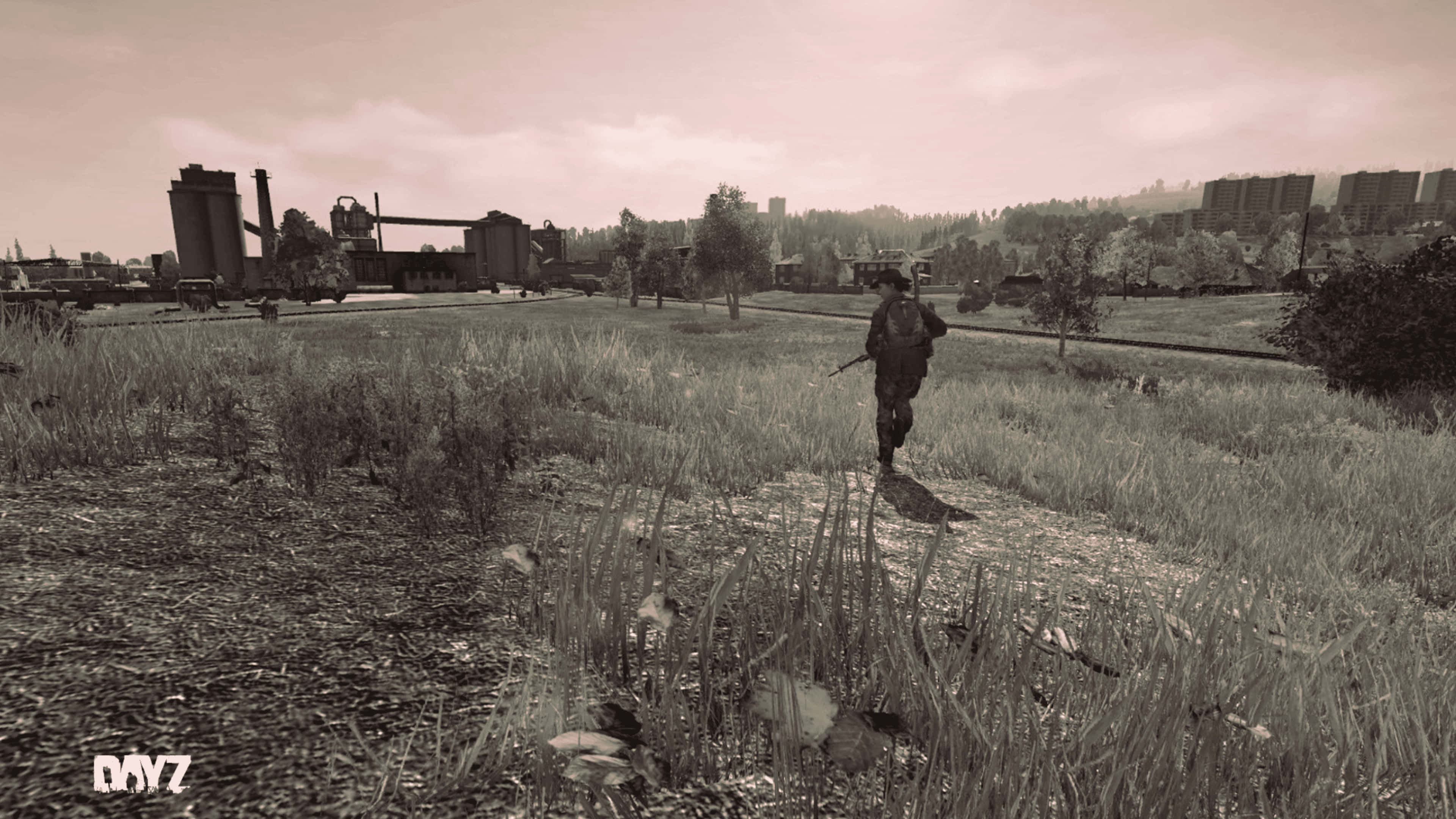 4K DayZ Epoch Mod 背景：奔跑中的角色 壁紙 — 一名孤獨的士兵穿過雜草叢生的草地，走向遠處的工業建築，天空朦朧。