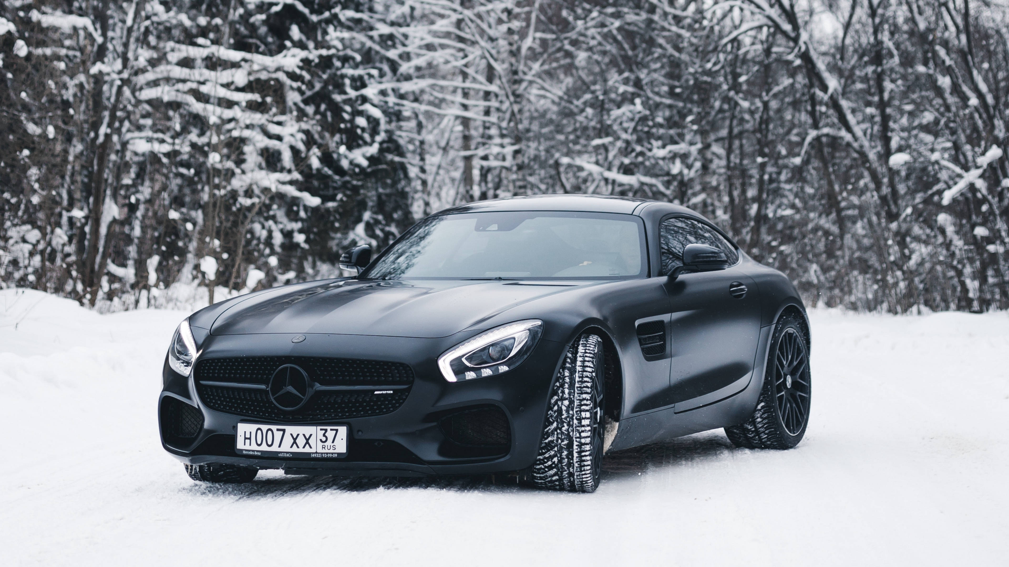 4K 黑色奔馳雪地 壁紙 — 一輛啞光黑色的Mercedes-AMG GT跑車停在深雪中，背景是積雪的樹木。