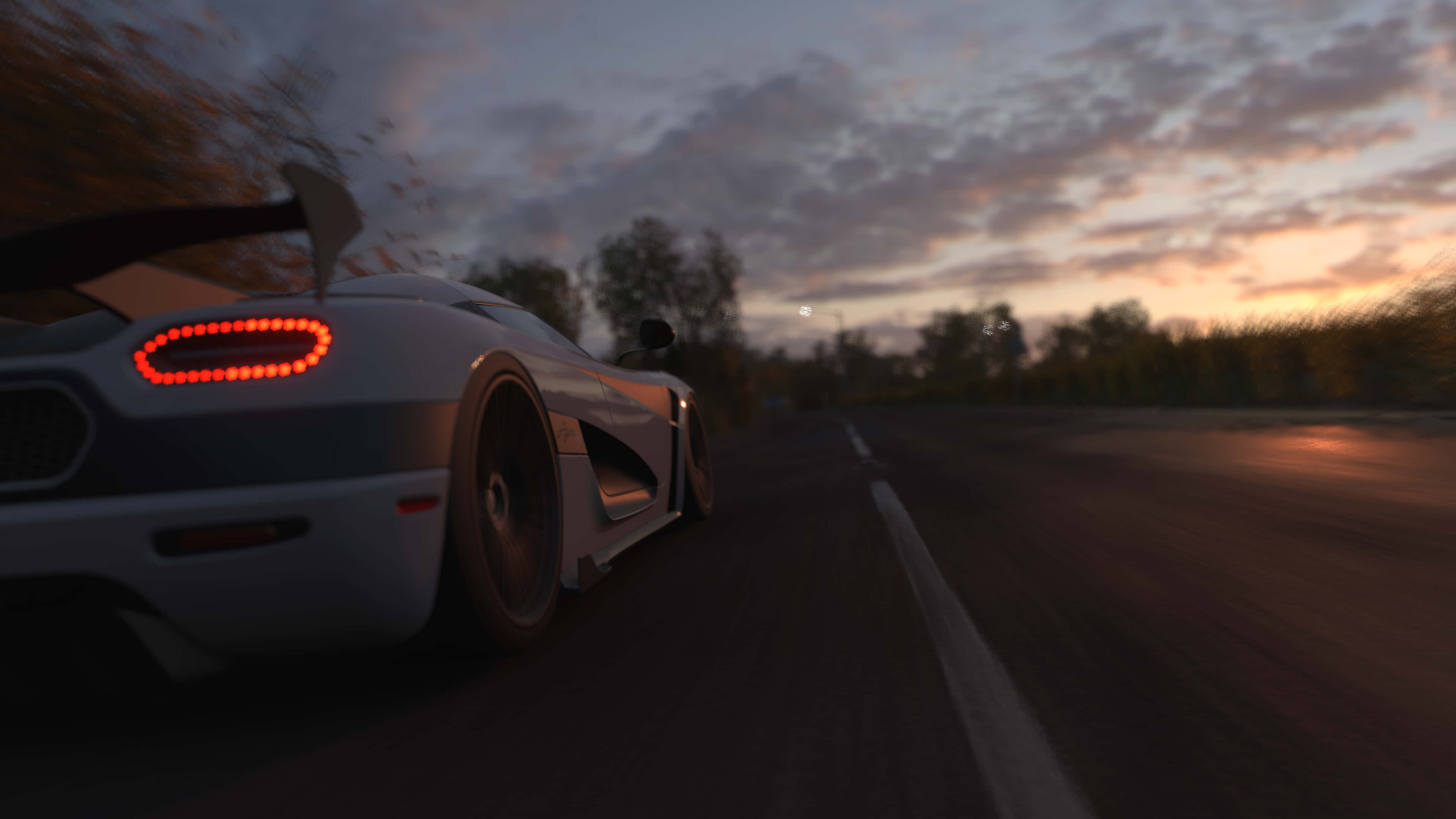 4K Forza Horizon 4 背景 - 白色Koenigsegg Agera 壁紙 — 一輛白色跑車在日落時分，以模糊的樹木和雲朵為背景，亮著紅色尾燈在公路上疾馳。