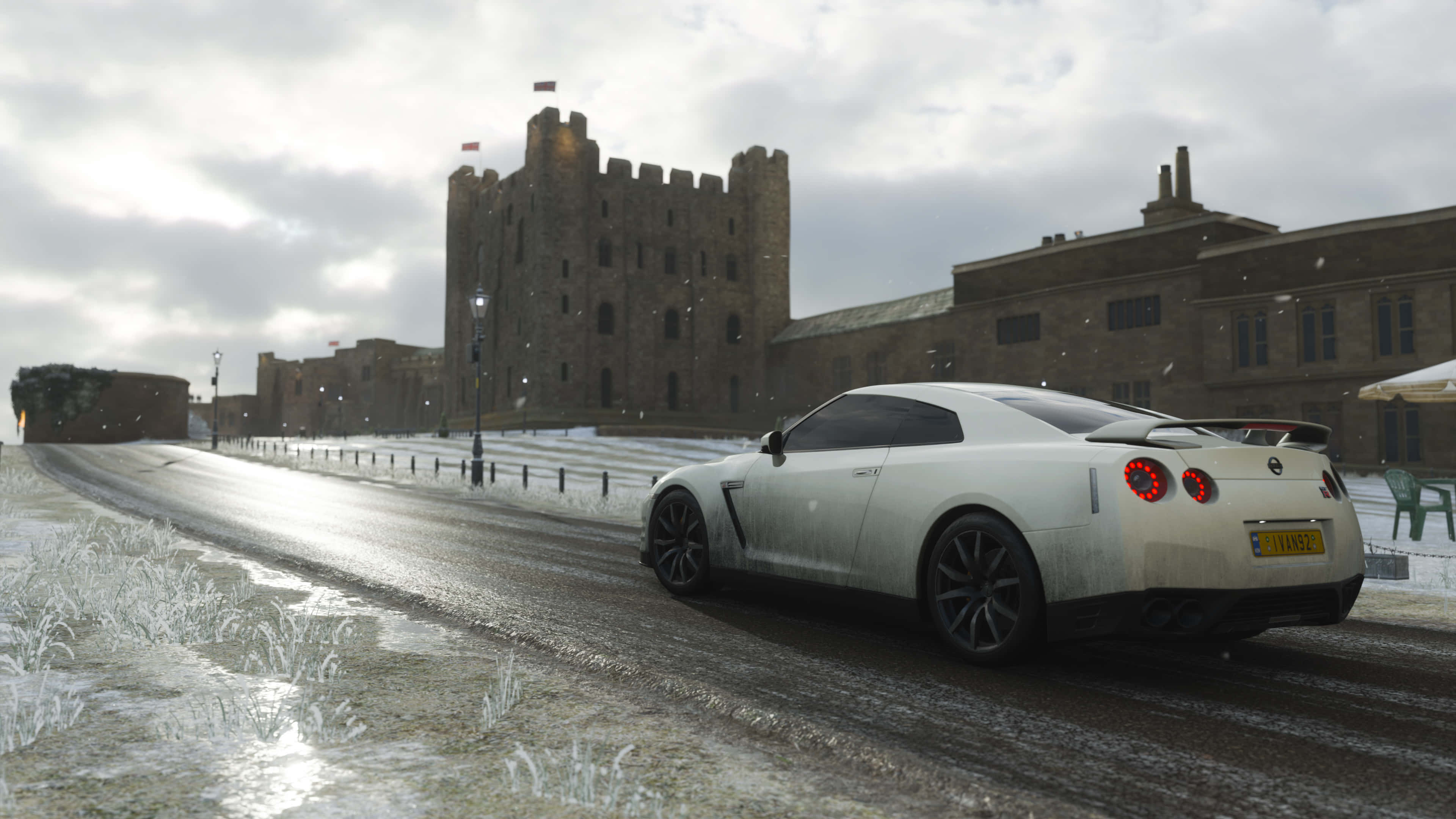 4K《Forza Horizon 4》背景：白色日產GT-R 壁紙 — 一輛白色跑車在雪路上行駛，經過一座歷史城堡，天空多雲的冬日。