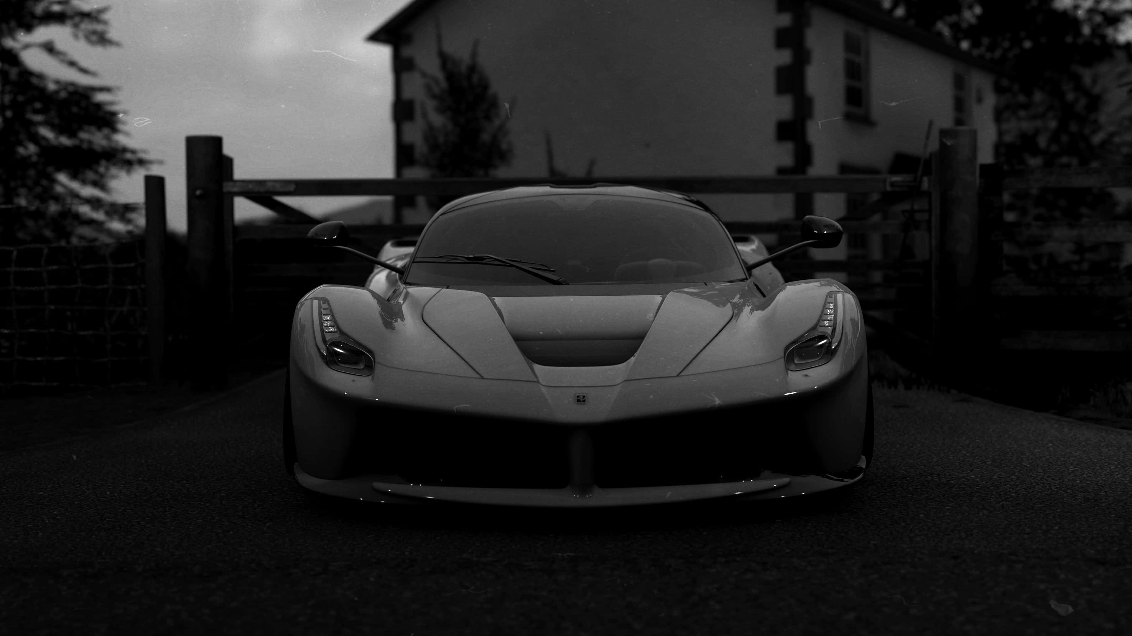 4K《Forza Horizon 4》背景：灰色LaFerrari 壁紙 — 一輛時尚跑車停放在質樸的大門前，背景是陰鬱的暮色天空。
