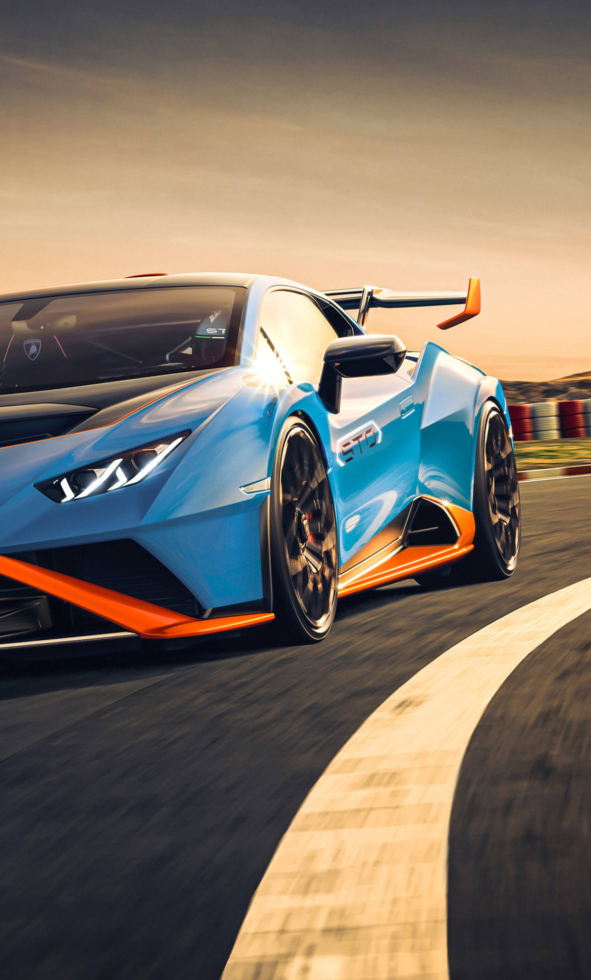 將奢華與性能融合於一身，4K Lamborghini iPhone！ 壁紙 — 一輛充滿活力的藍色和橙色林寶堅尼 Huracán STO 在日落時分沿著彎曲的賽道奔馳，動態模糊強調了速度。