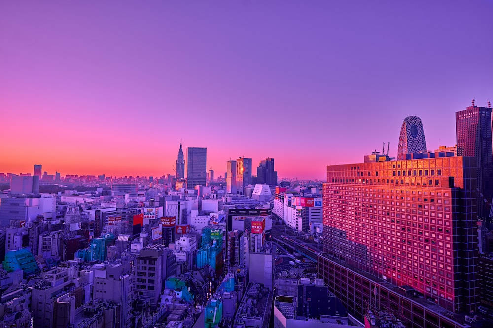 日落時分，廣闊的城市景觀，天空呈現紫色和粉紅色，建築物閃閃發光。