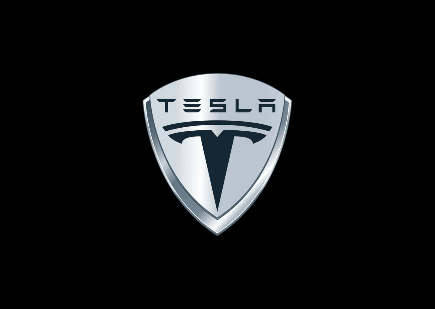 4K 解析度特斯拉標誌 壁紙 — 一個光滑的銀色 Tesla 標誌盾牌徽章，居中於帶有金屬光澤的純黑色背景上。
