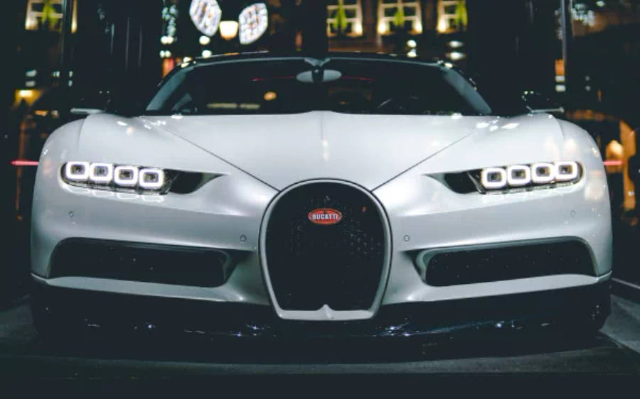 白色布加迪奇龍 4K 壁紙 — 一輛時尚的銀色Bugatti Chiron在昏暗的城市車庫中，在霓虹燈下閃閃發光。