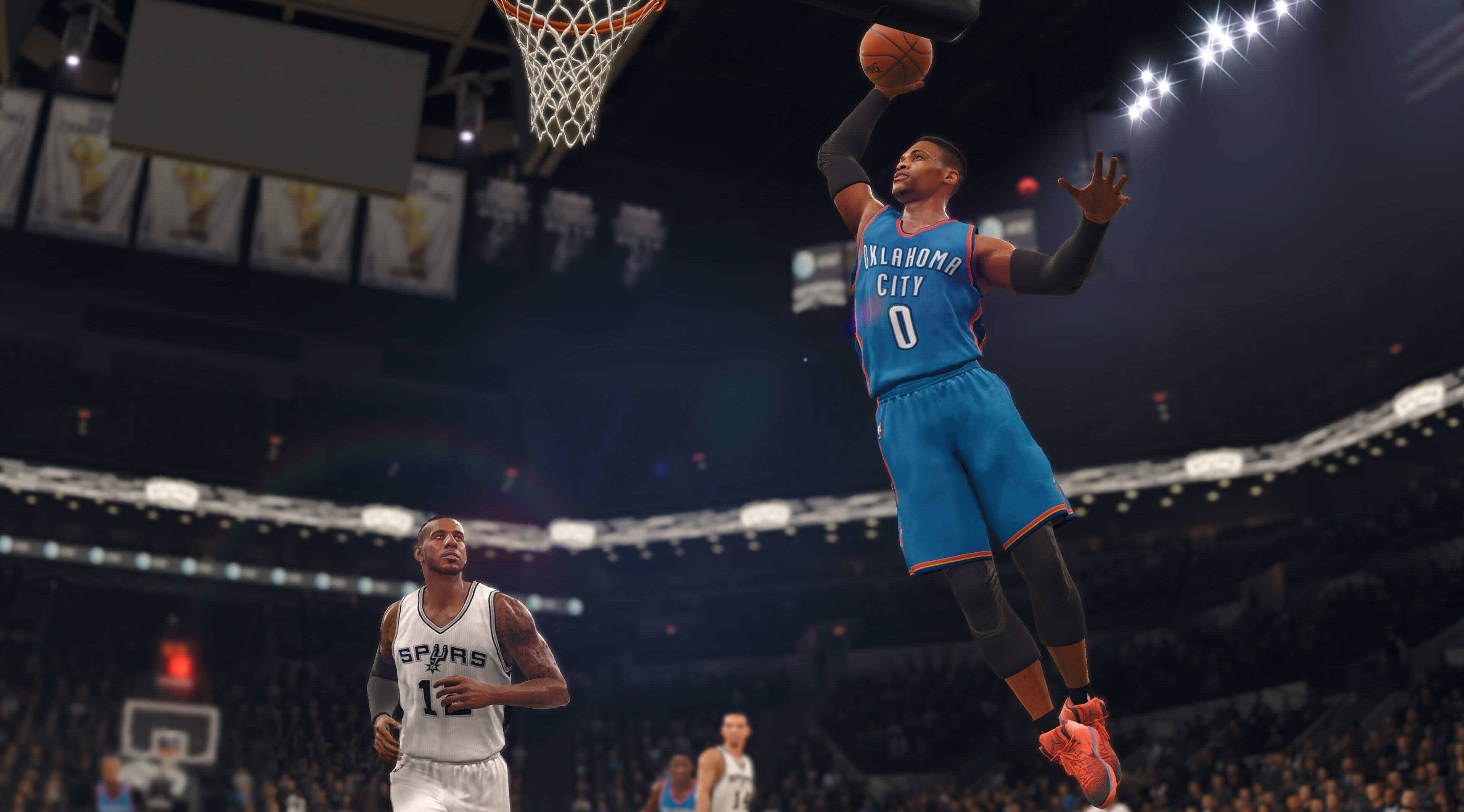 4K NBA魯斯·威斯布魯克灌籃 壁紙 — 一名身穿藍色奧克拉荷馬城球衣的籃球運動員正在入樽，而一名馬刺球員在擠滿觀眾的場館下方觀看。
