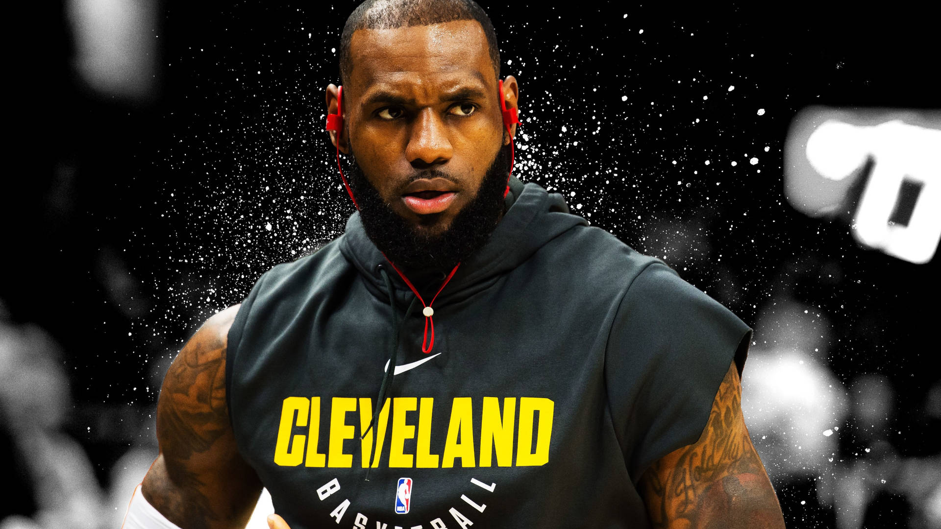 4K NBA勒布朗·詹姆斯訓練 壁紙 — 勒邦占士身穿黑色無袖連帽衛衣，上面有黃色字樣 'CLEVELAND BASKETBALL'，在帶有白色斑點的黑色背景下凝視着。