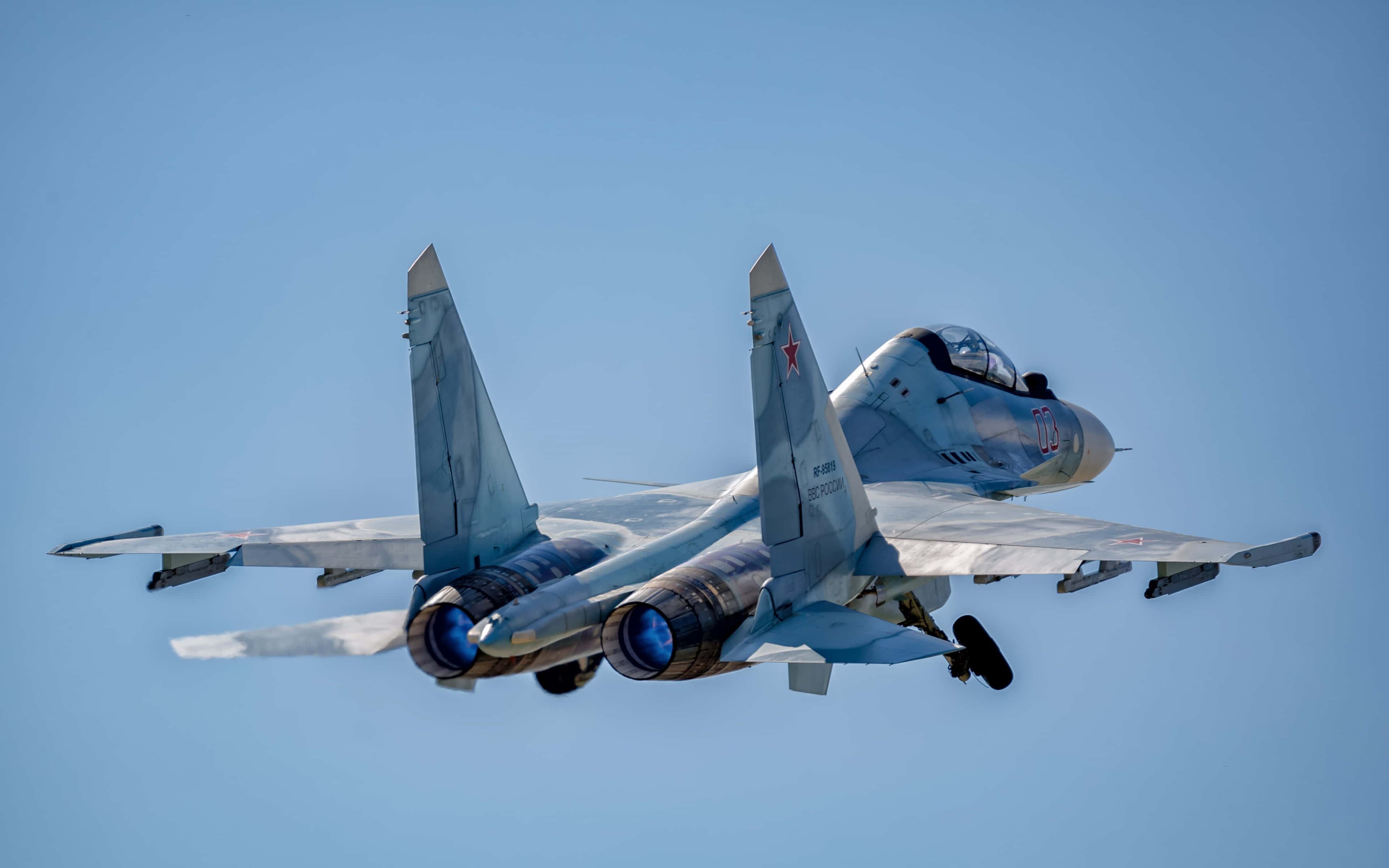 4K畫質下士兵列隊行軍 壁紙 — 一架灰色戰鬥機在晴朗的藍天中翱翔，起落架放下，後燃器發光。