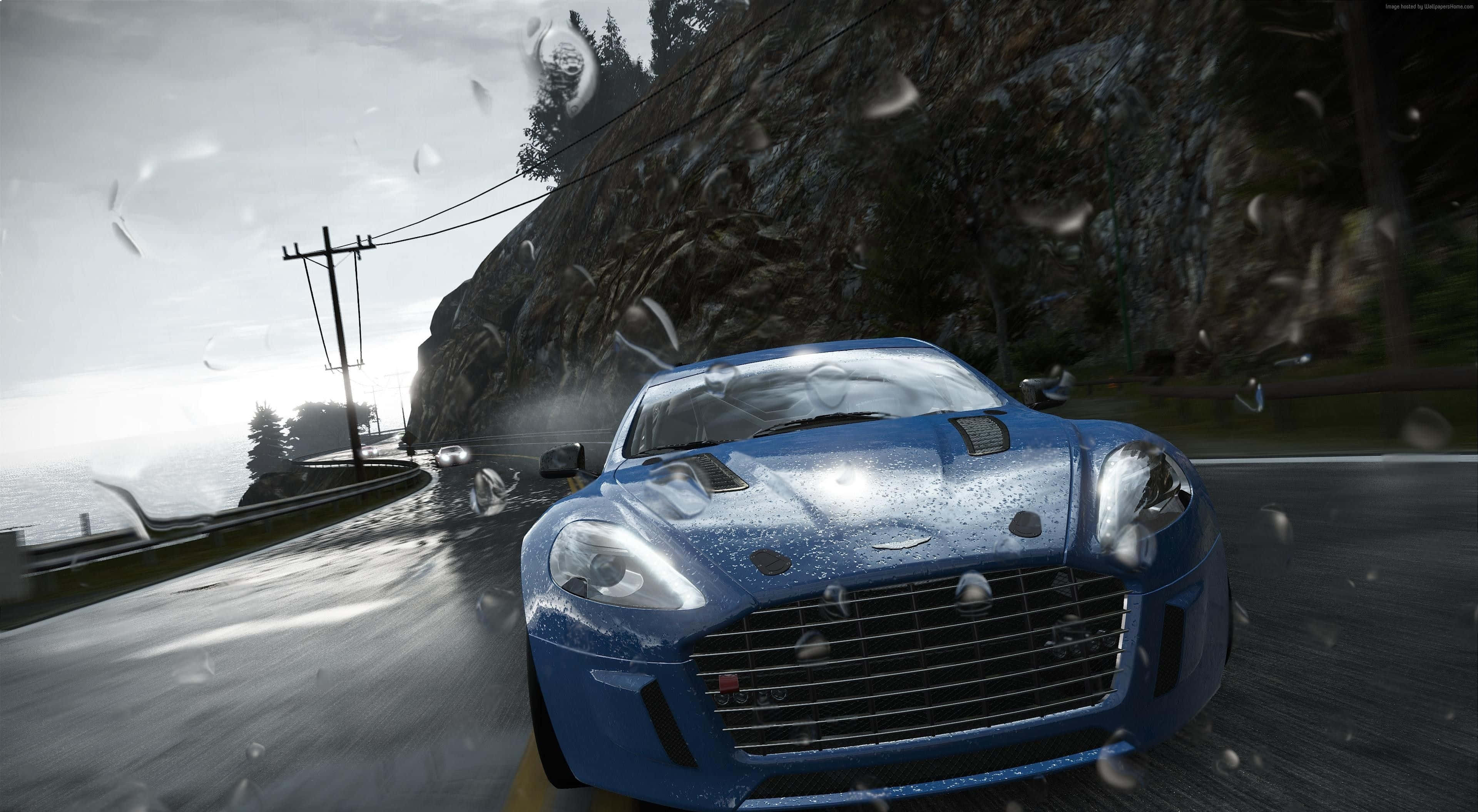 4K Project Cars 淺藍色 Aston Martin DBS 背景 壁紙 — 一輛藍色跑車在濕滑的海岸公路上飛馳，雨滴在空中飛舞。