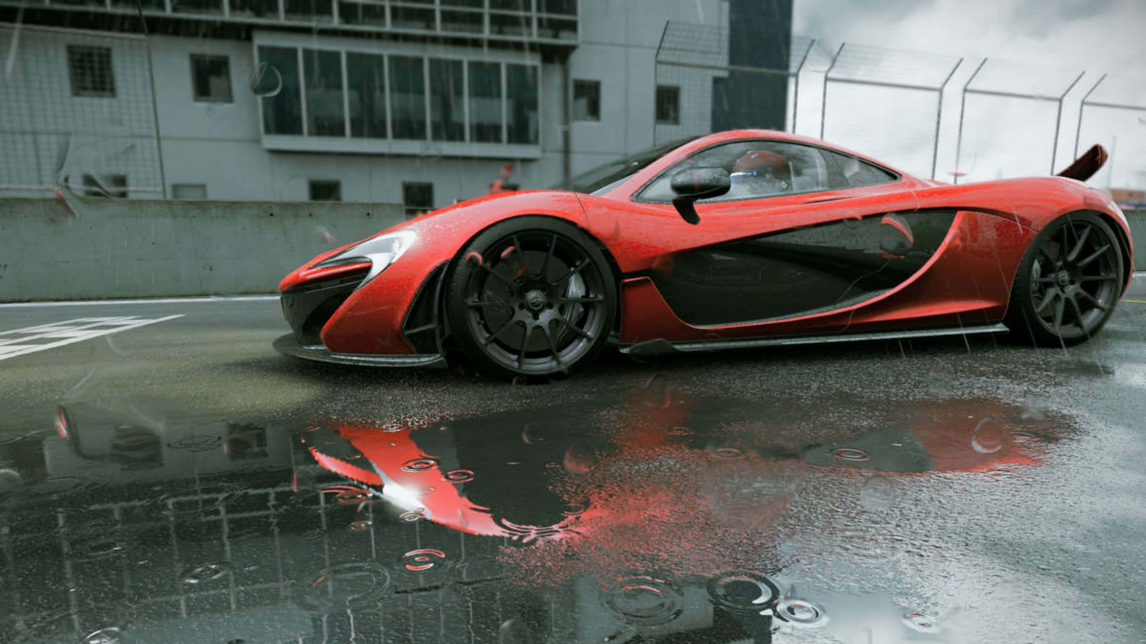 4K Project Cars 紅色麥拉倫 P1 背景 壁紙 — 一輛鮮紅色的McLaren跑車在潮濕的賽道上閃閃發光，雨滴在水坑中泛起漣漪，映照出其流線型車身。