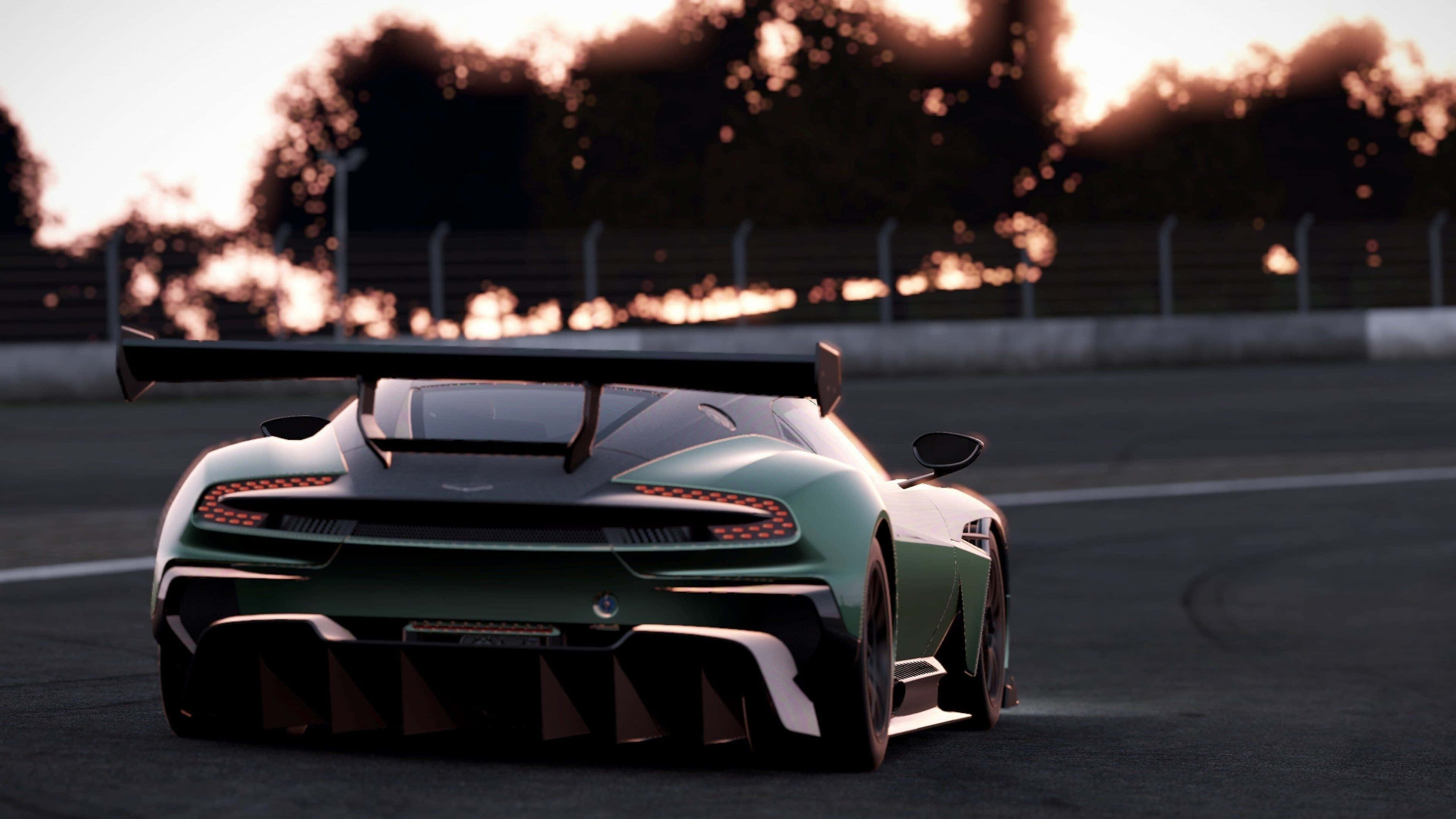 4K Project Cars 綠色 Aston Martin Vulcan AMR 背景 壁紙 — 一架時尚的綠色賽車，帶有大型後翼，在日落時分沿著賽道飛馳，尾燈閃爍，背景樹木模糊。