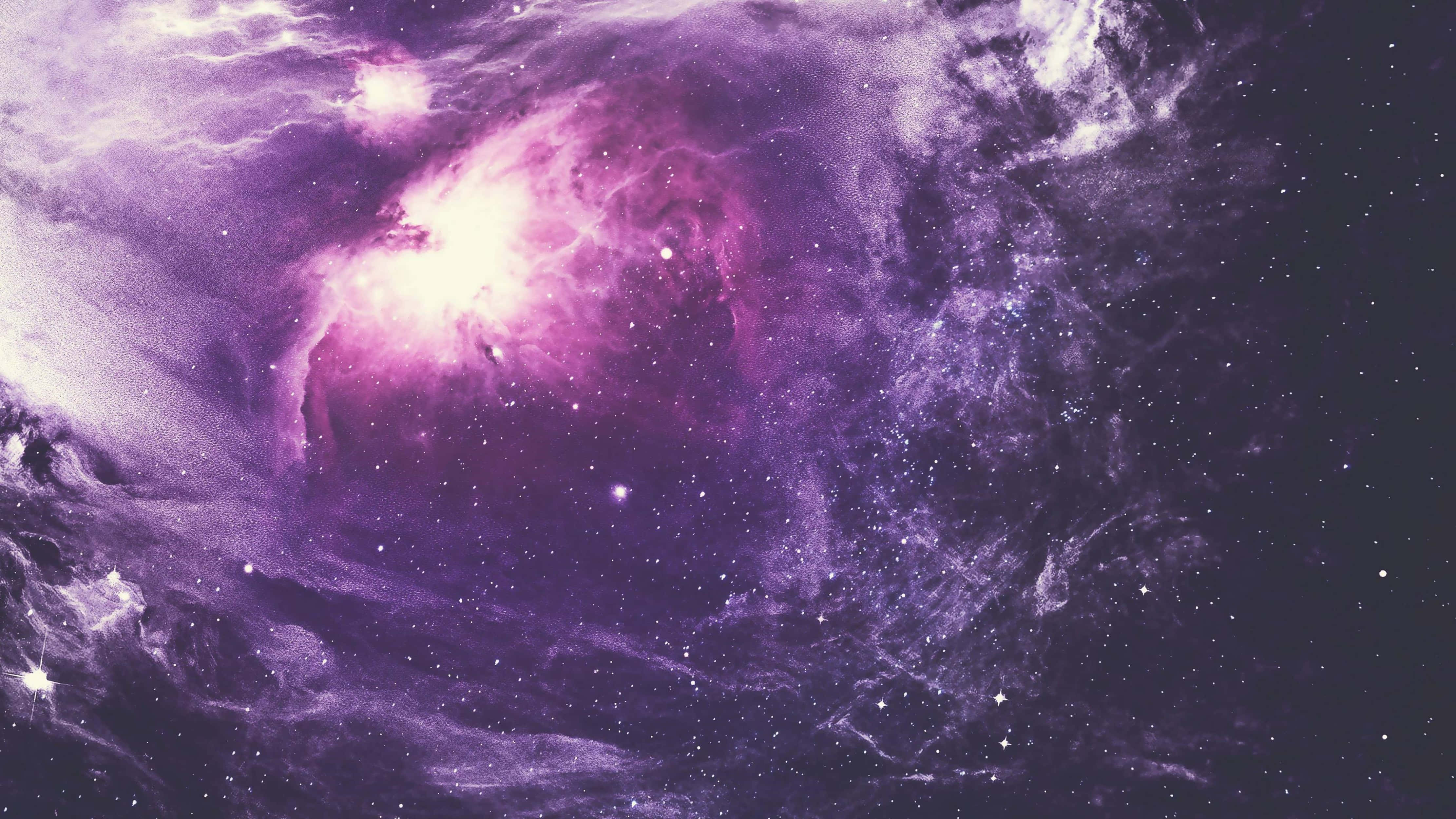 4K宇宙紫色星雲 壁紙 — 一個充滿活力的紫色星雲在黑暗的宇宙背景下，伴隨著發光的氣體和散落的星星旋轉。