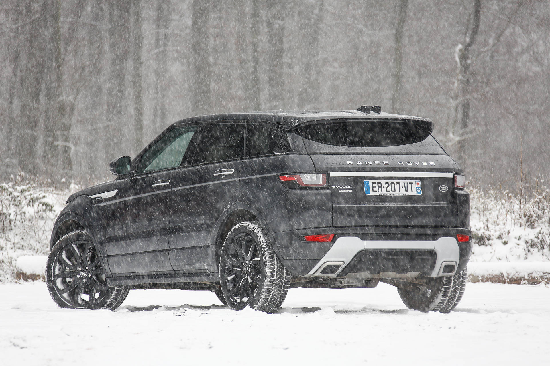 黑色 Range Rover Evoque 在冬季暴風雪中行駛於積雪森林。