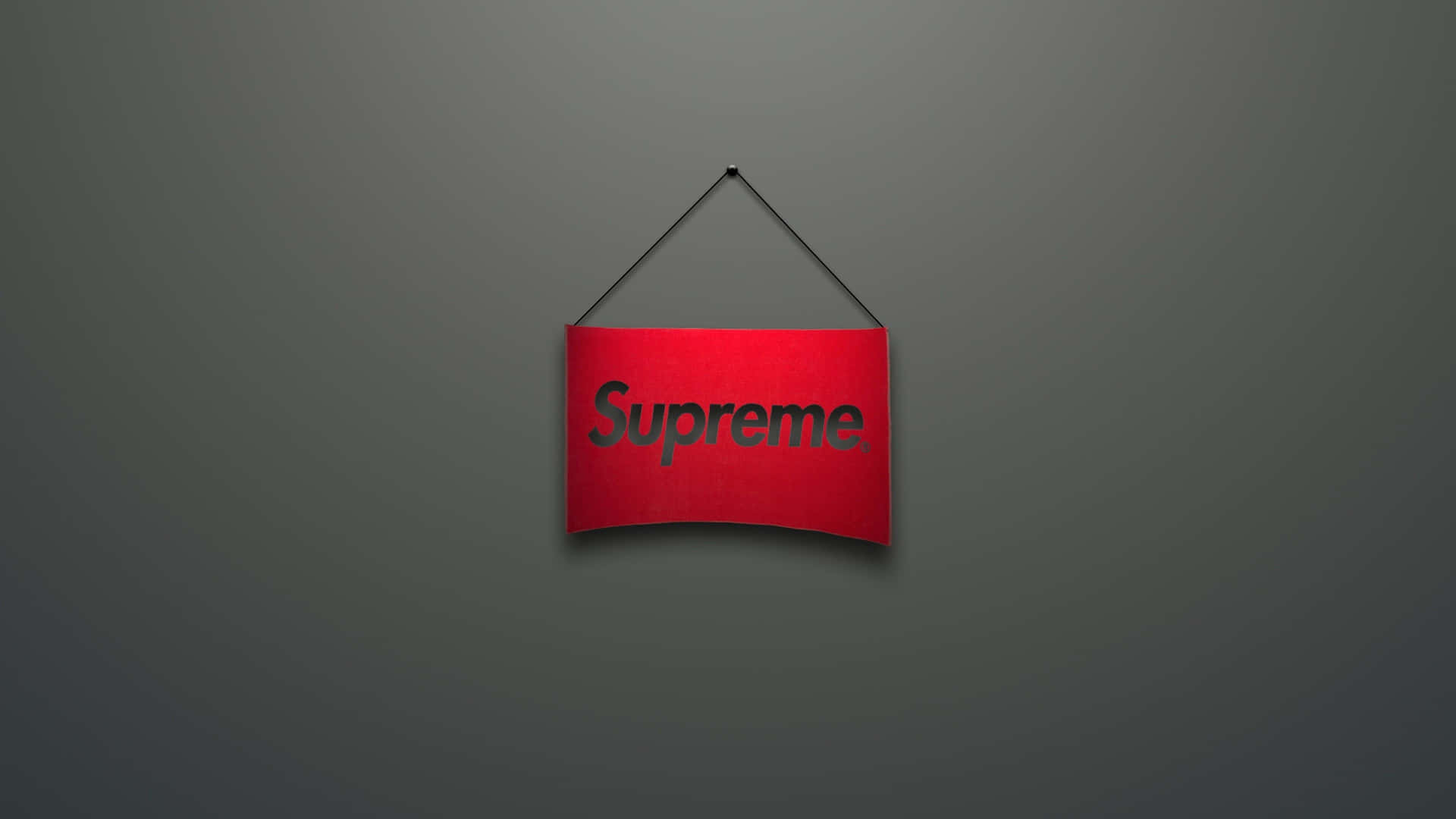 紅色Supreme標誌牌掛在灰色牆上。