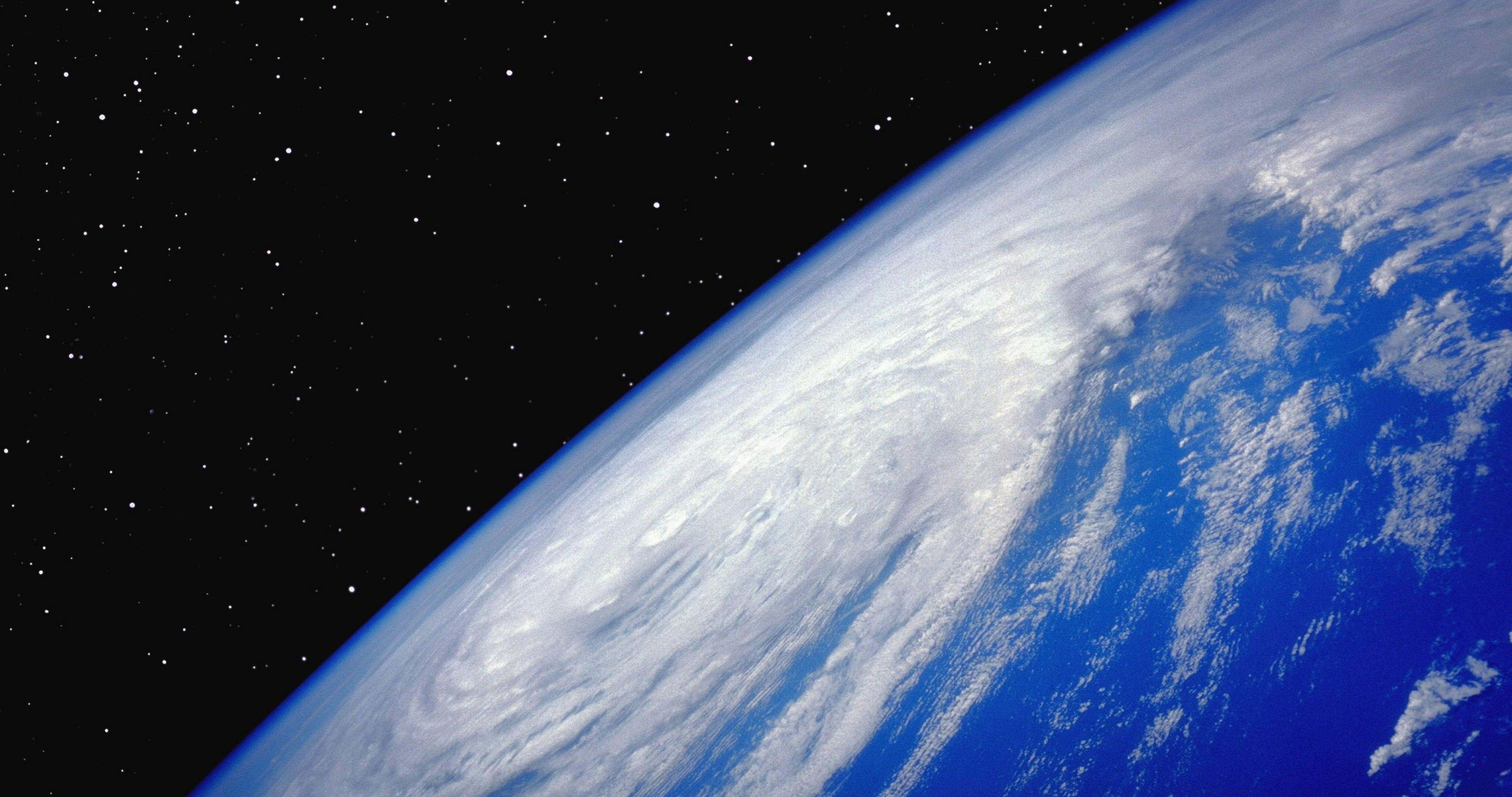 4K 地球旋渦雲 壁紙 — 從太空俯瞰地球的壯麗景色，展現深藍色海洋上旋轉的白色雲層，背景是佈滿星星的黑色天空。