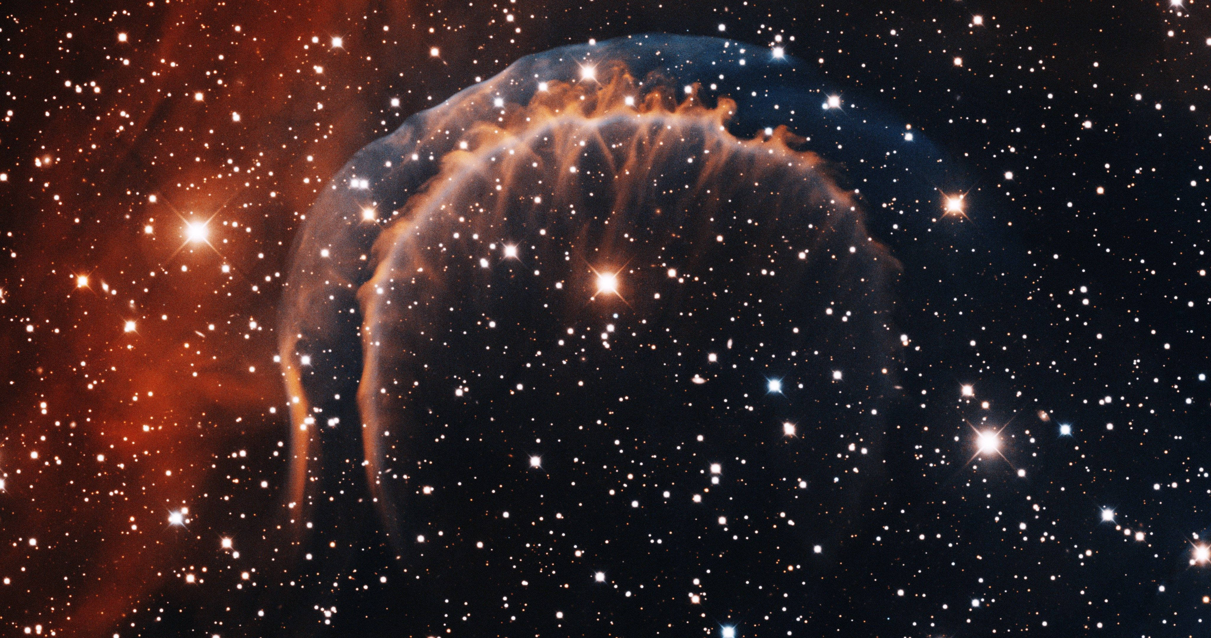 4K 超高清銀河明亮星群 壁紙 — 一個發光的宇宙星雲，帶有火熱的橙色觸手和明亮的星星，背景是深邃的黑色太空。