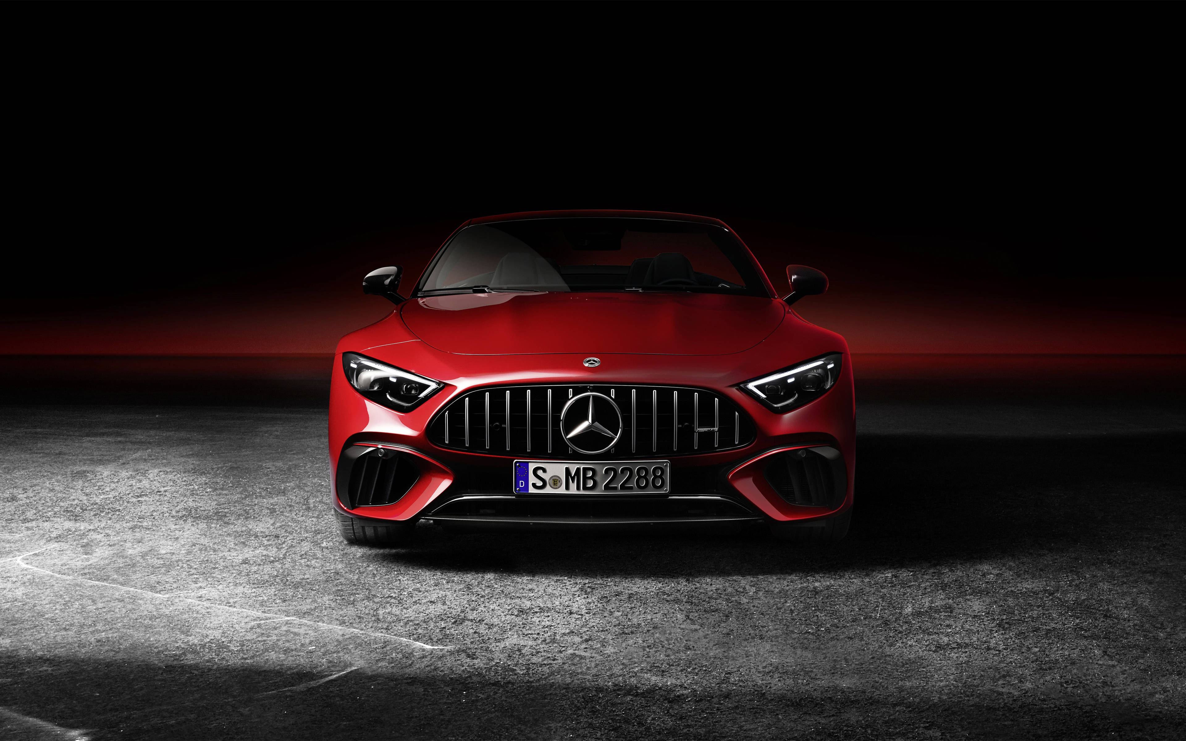 4K 奔馳紅色 壁紙 — 一輛引人注目的紅色 Mercedes-AMG 跑車在戲劇性燈光下閃閃發光，背景是黑暗的攝影棚和發光的紅色地平線。
