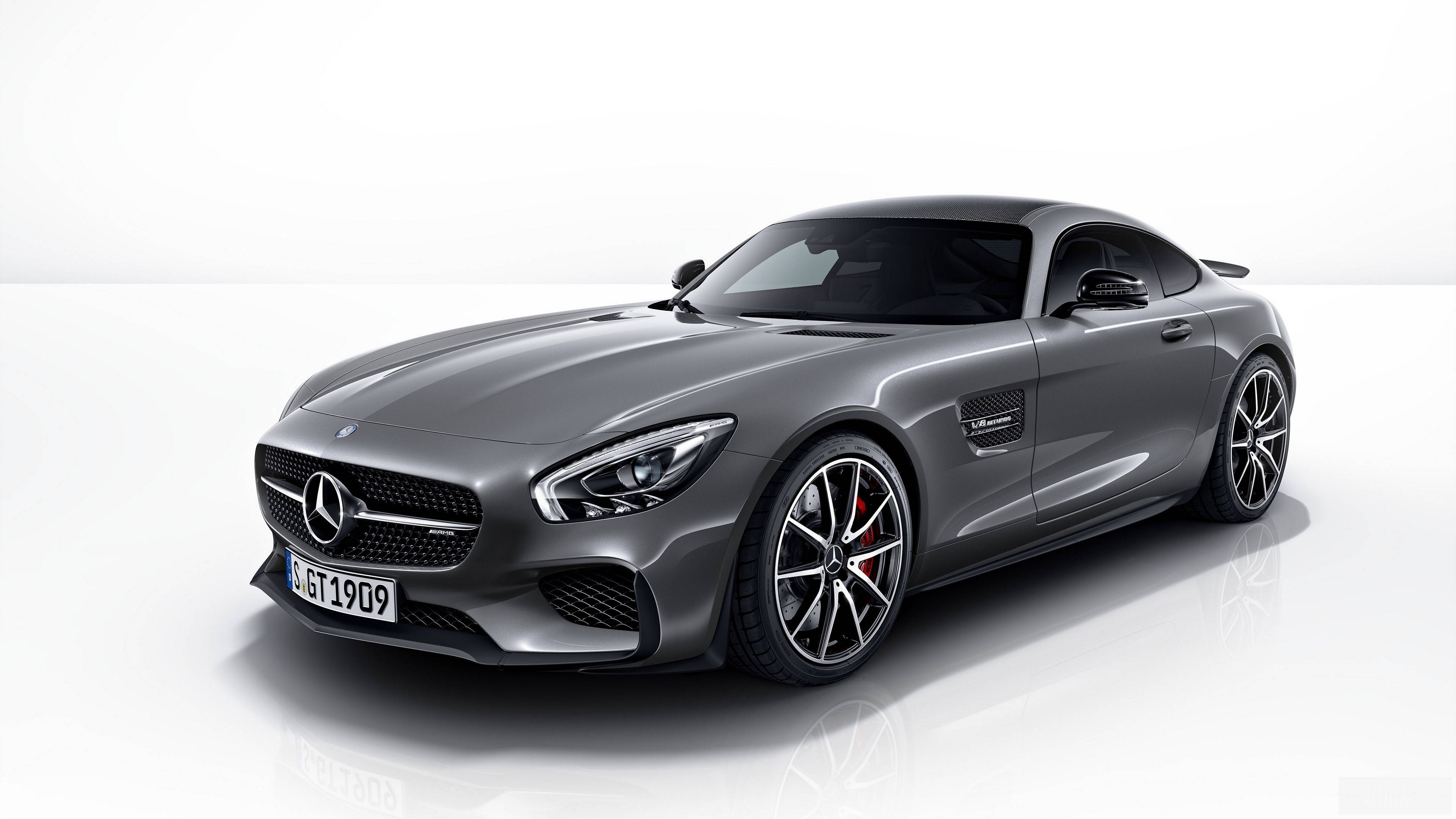 4K 奔馳 AMG GT 壁紙 — 一輛時尚的銀色 Mercedes-AMG GT 跑車在攝影棚燈光下，在純白反光地板上閃閃發光。