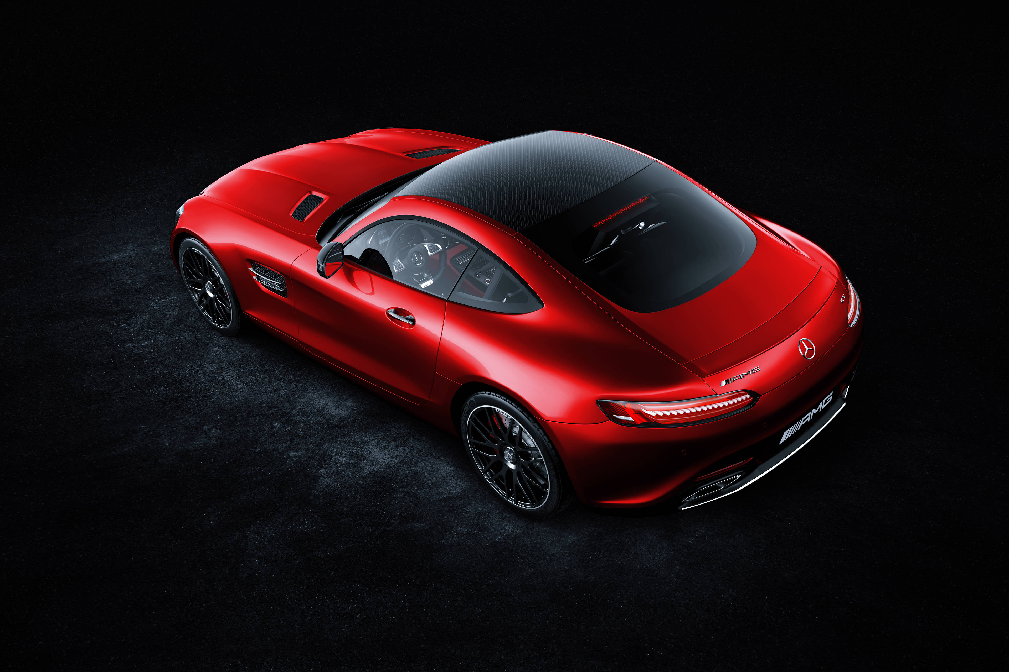 4K 奔馳 GT 級紅色 壁紙 — 一輛光亮的紅色Mercedes-AMG GT跑車配備碳纖維車頂，從高角度展示在深色紋理工作室地板上。