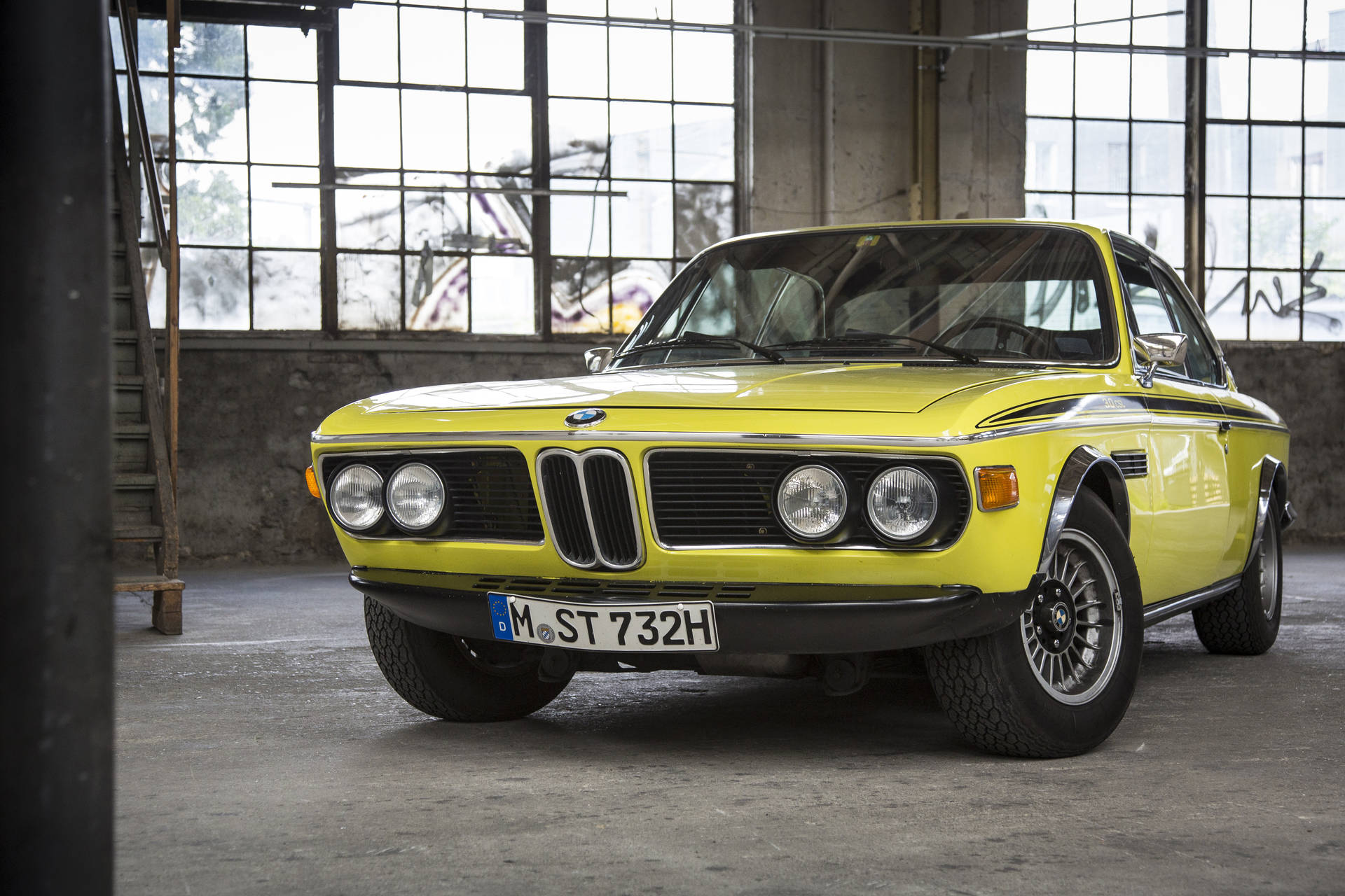 復古黃色BMW 2002 Turbo停放在一個有塗鴉的工業倉庫內。 — 4K BMW 壁紙 壁紙