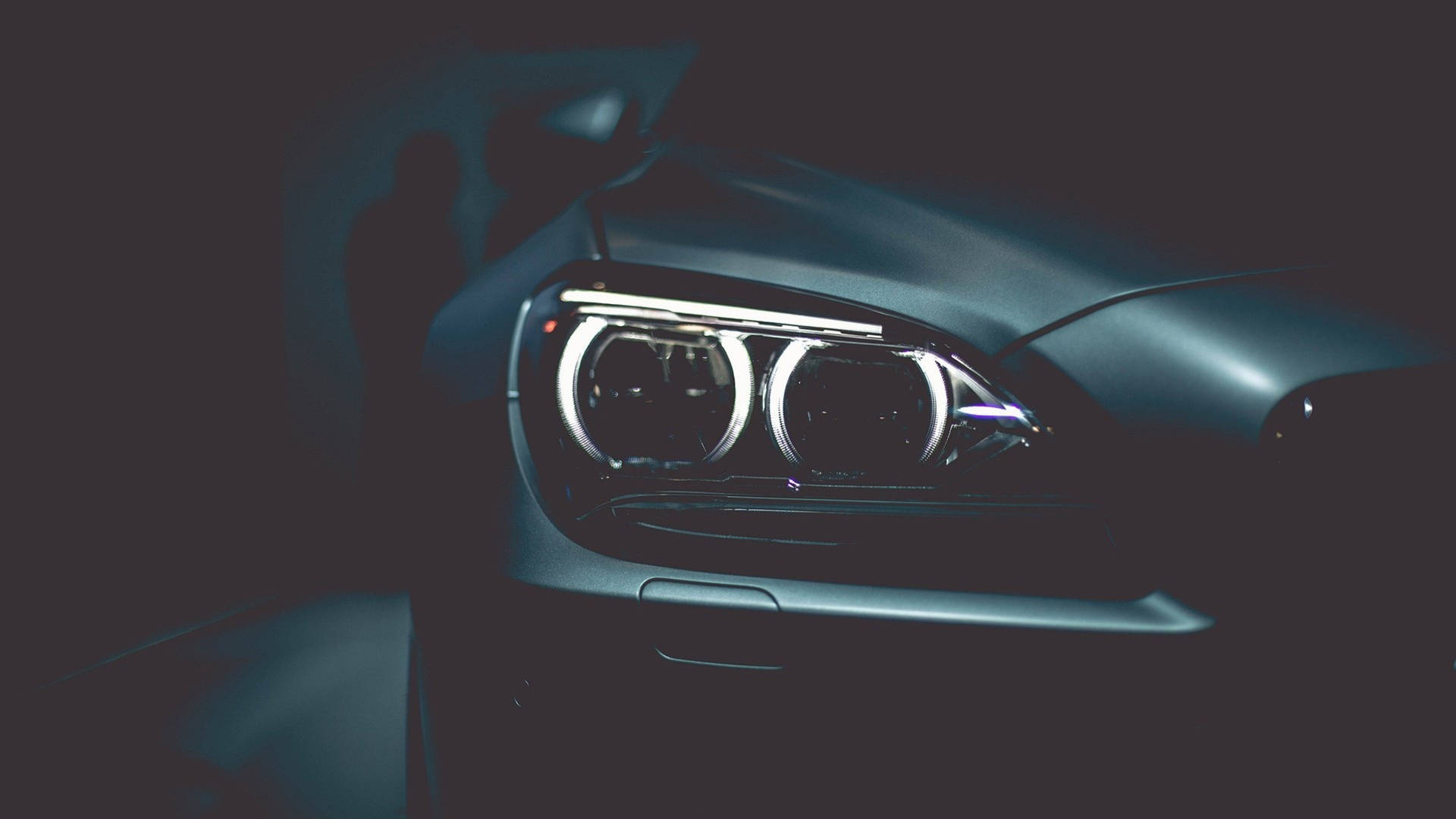 時尚汽車車頭燈在黑暗中發光，背後有陰影輪廓。 — 4K BMW 壁紙 壁紙