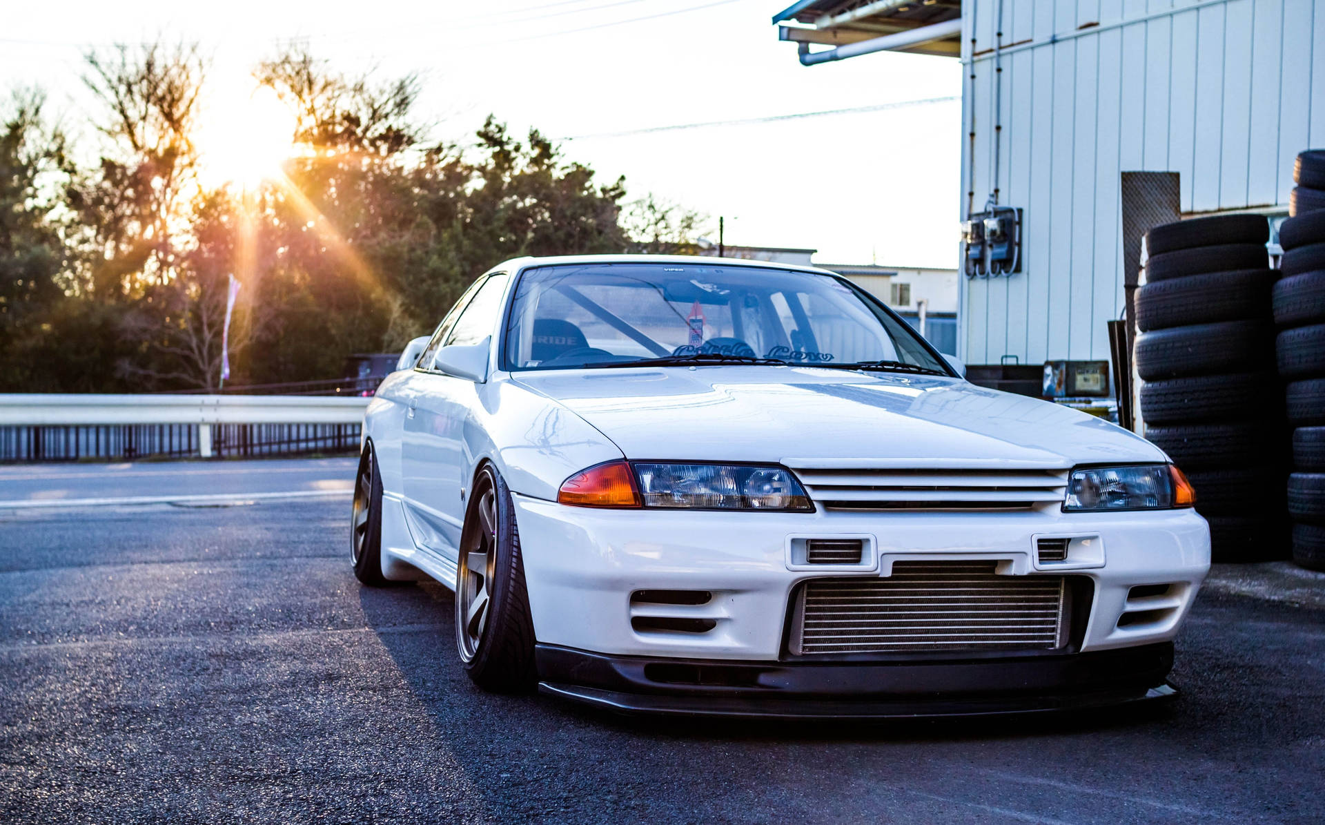 白色日產Skyline R32在日落時停放在輪胎堆附近。