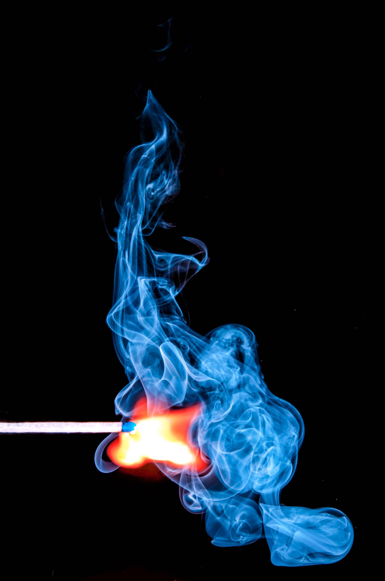 一根燃燒的火柴，在黑色背景上冒出藍煙